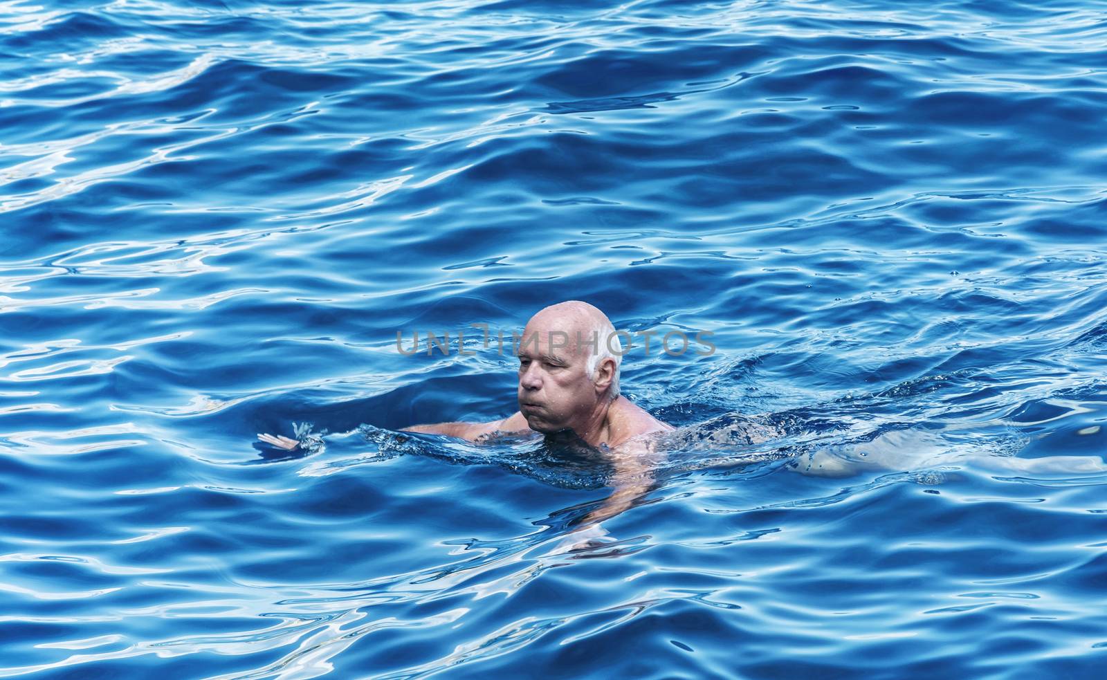 A man of mature age with gray hair bathes in water