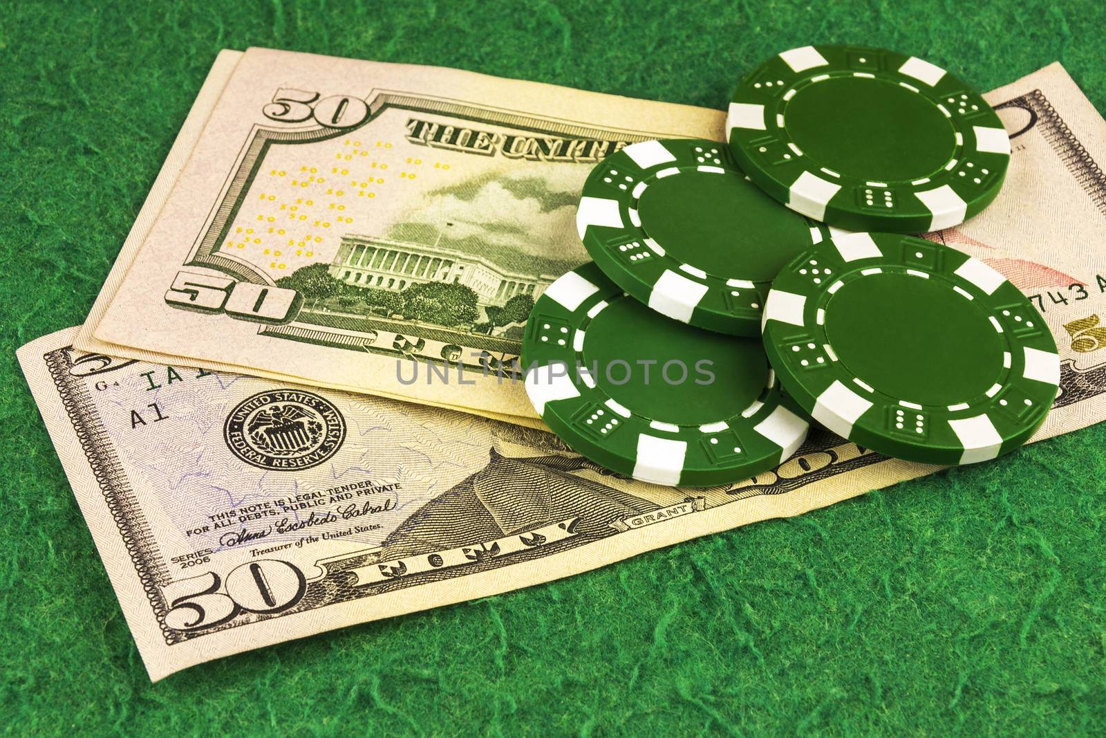 Four green chips lie on bills $ 50 by Grommik