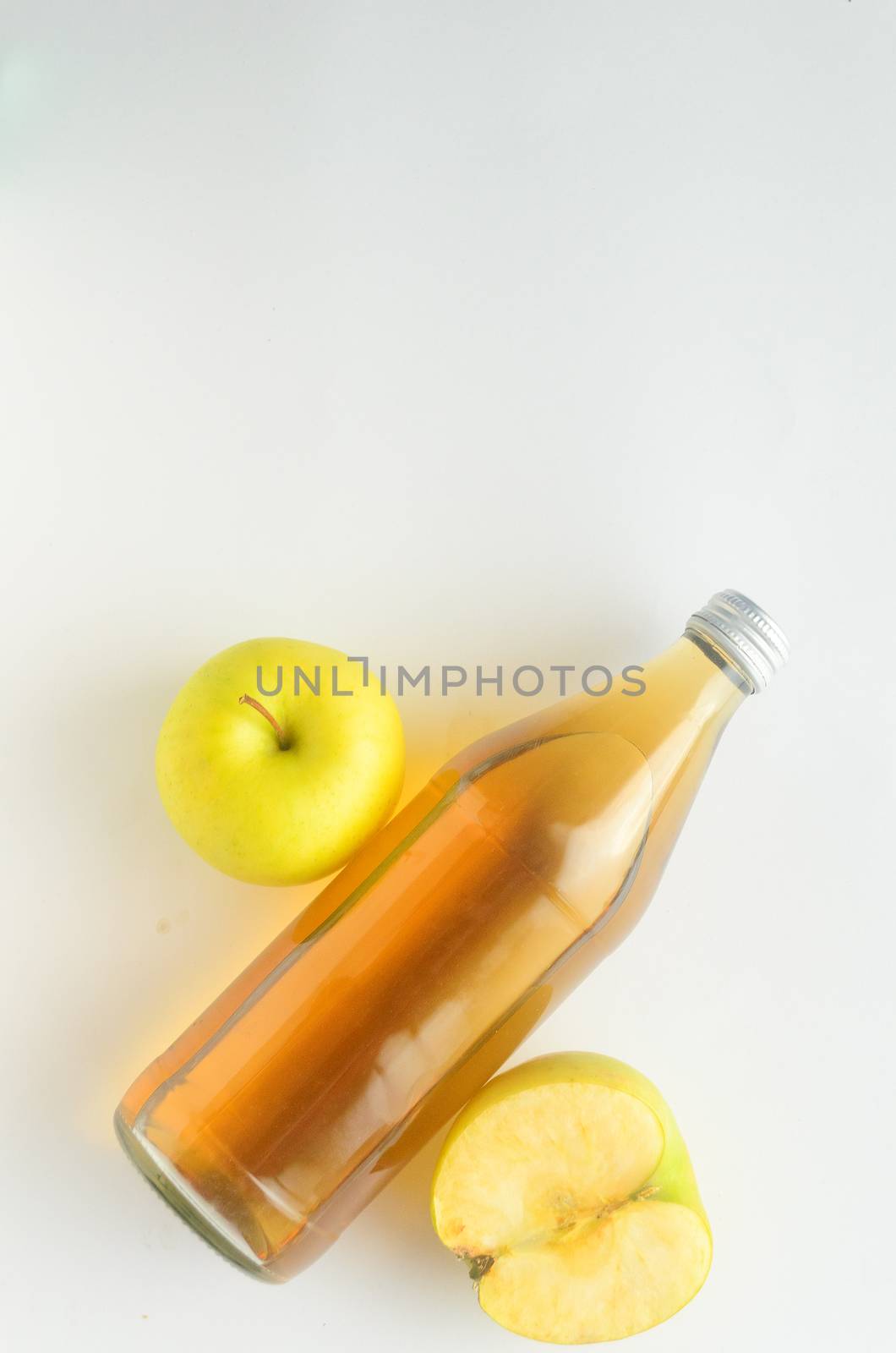 Top view, a bottle of apple cider vinegar and green apples on white background. by andre_dechapelle