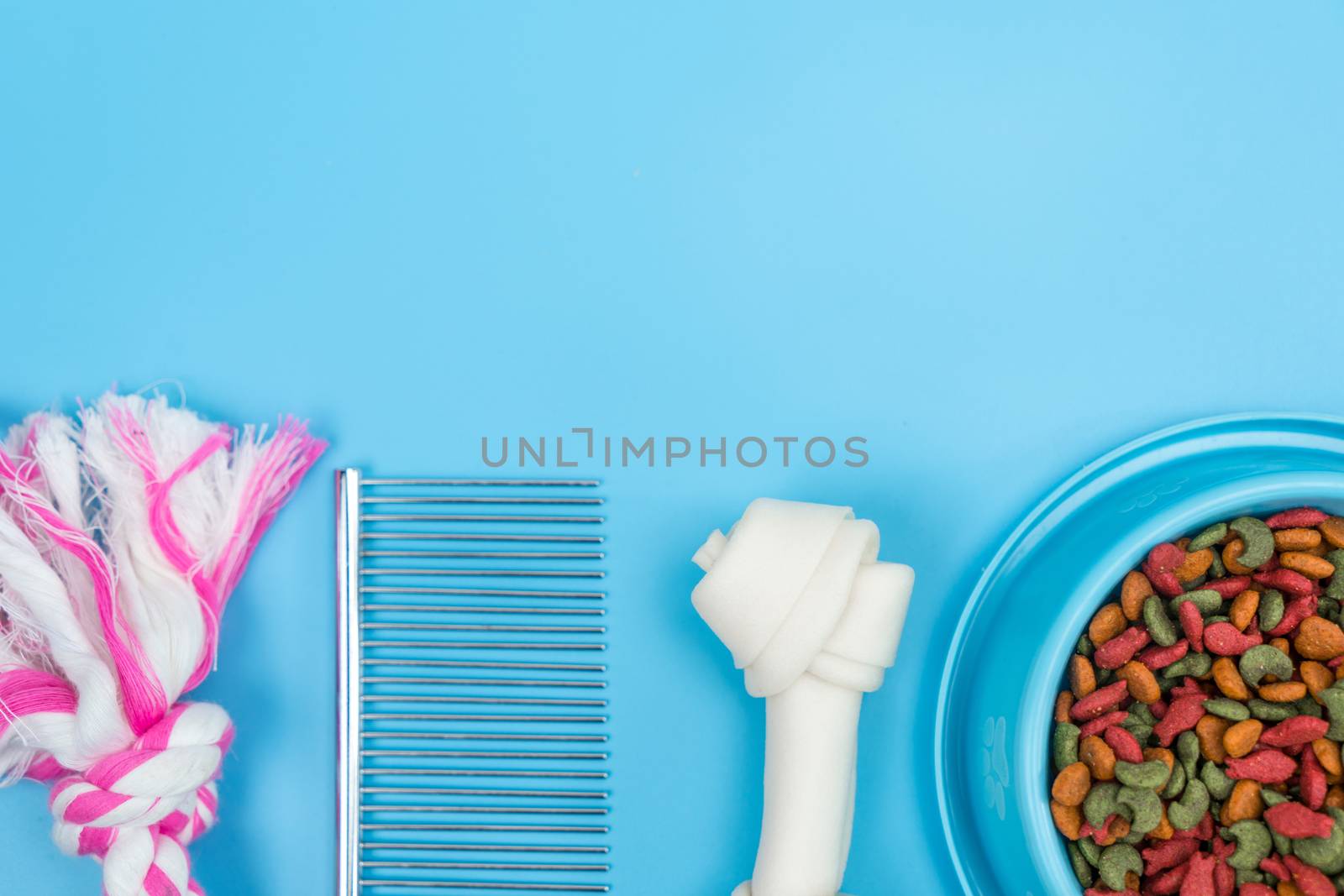 Dry food in bowls with bone, toy, for pets on color background