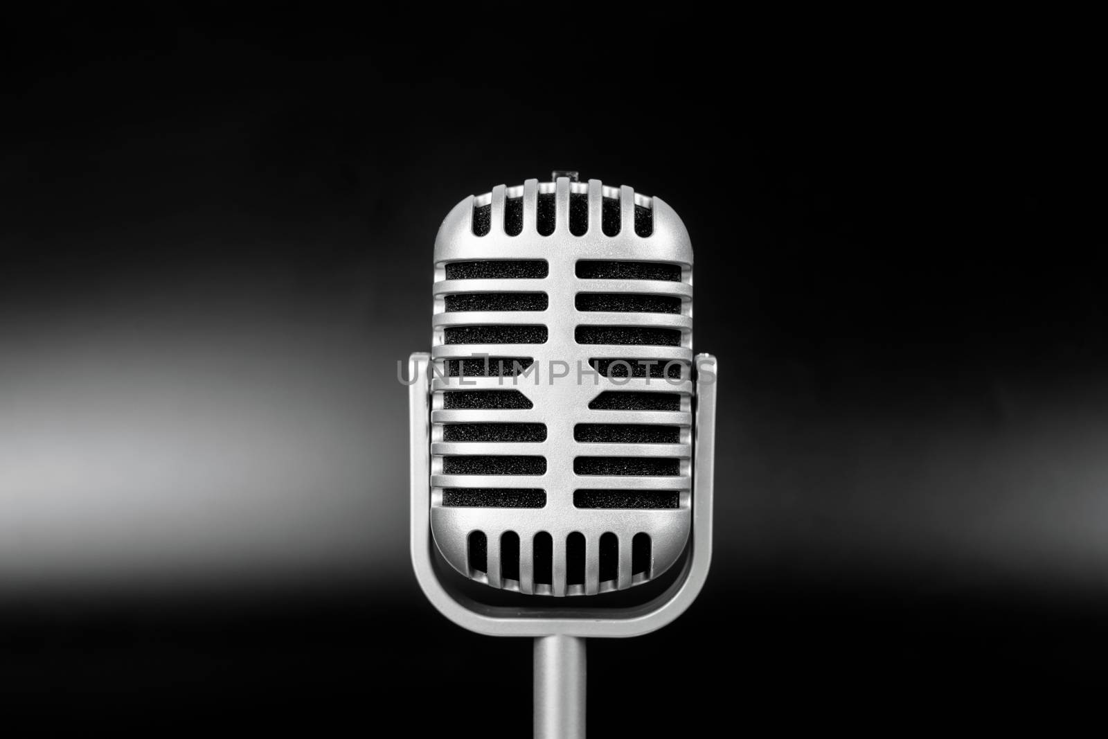 Retro microphone of silver on black background