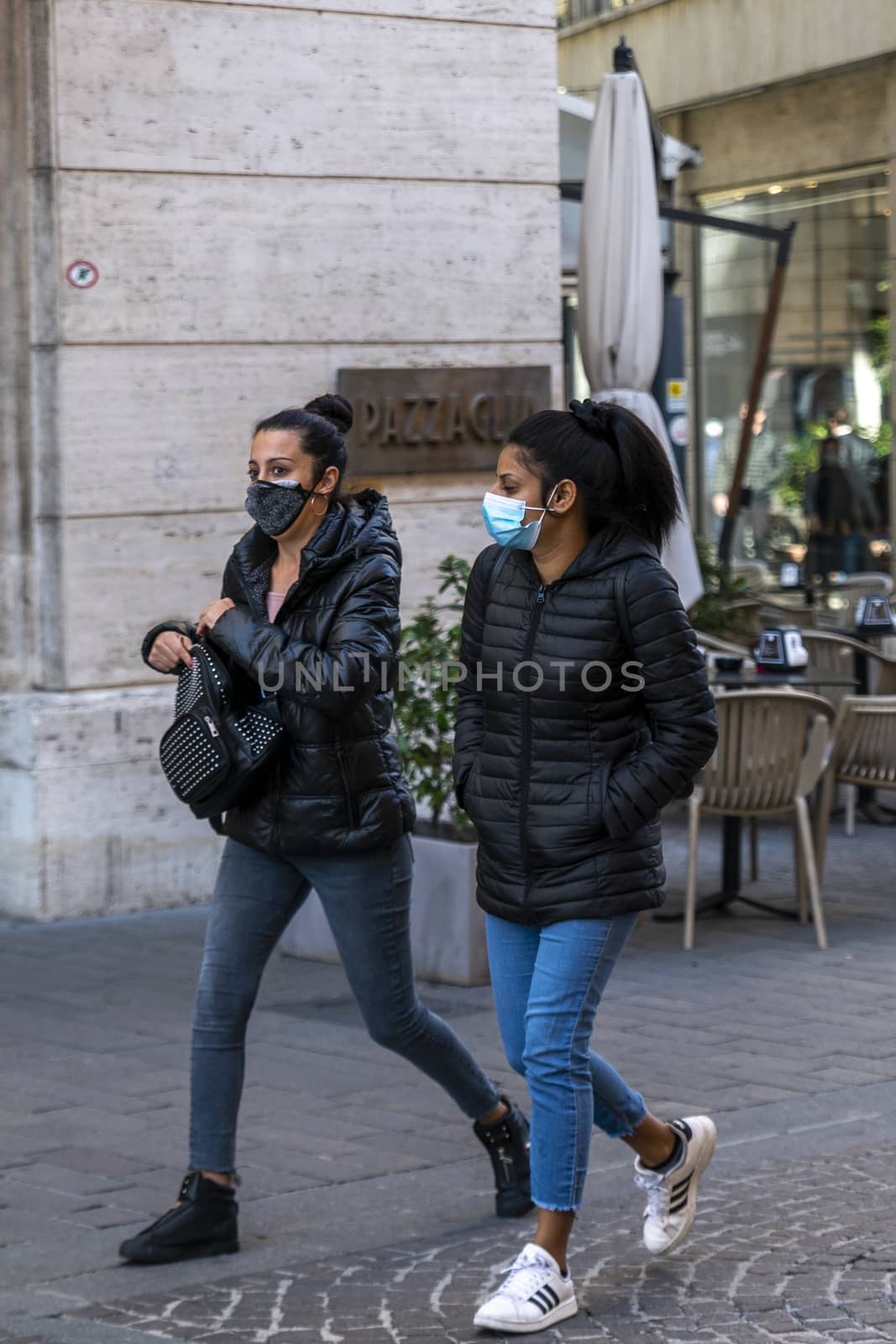 two women with medical mask walking in the city center by carfedeph