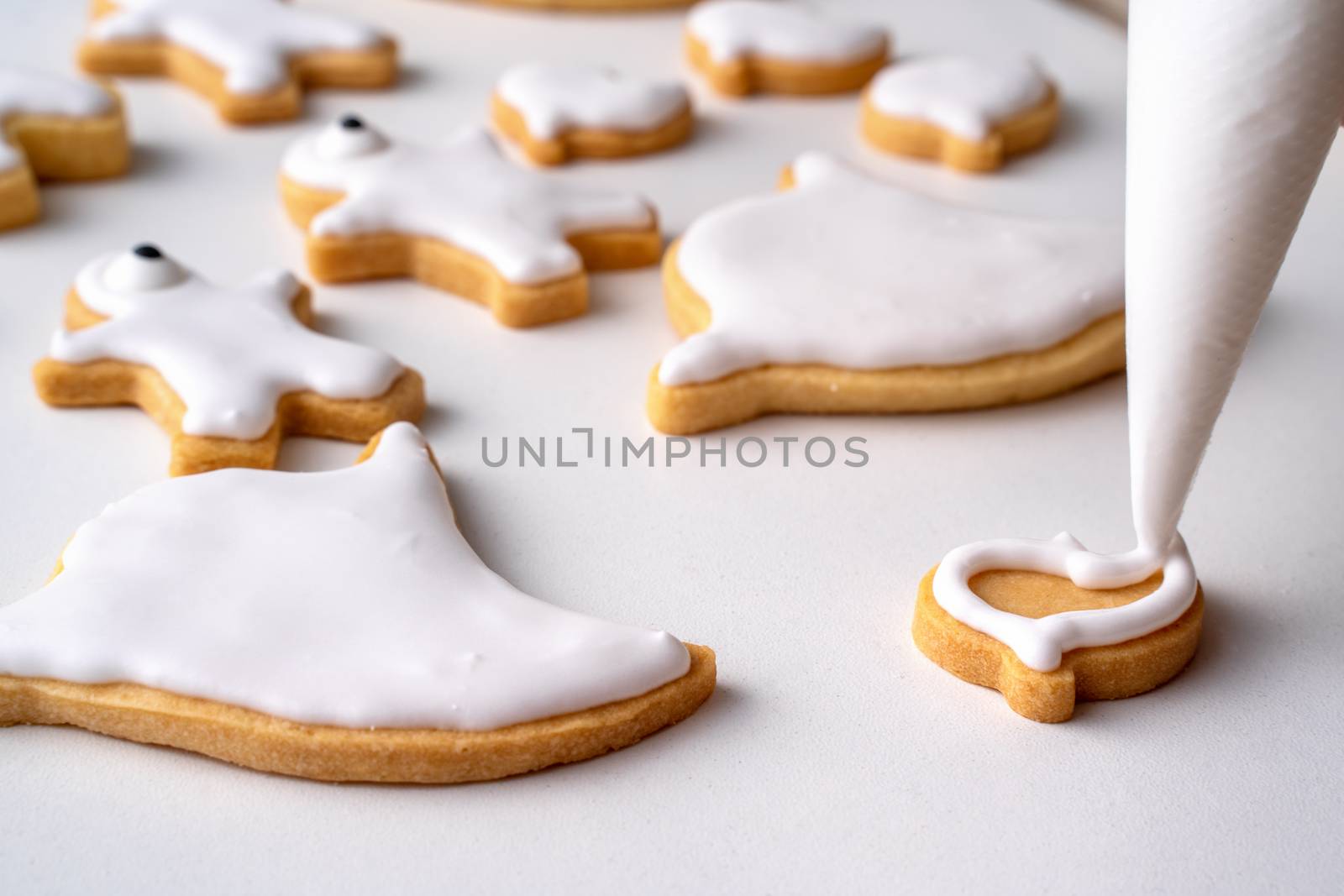 Close up of decorating cute Halloween gingerbread cookies with frosting icing cream topping bag.