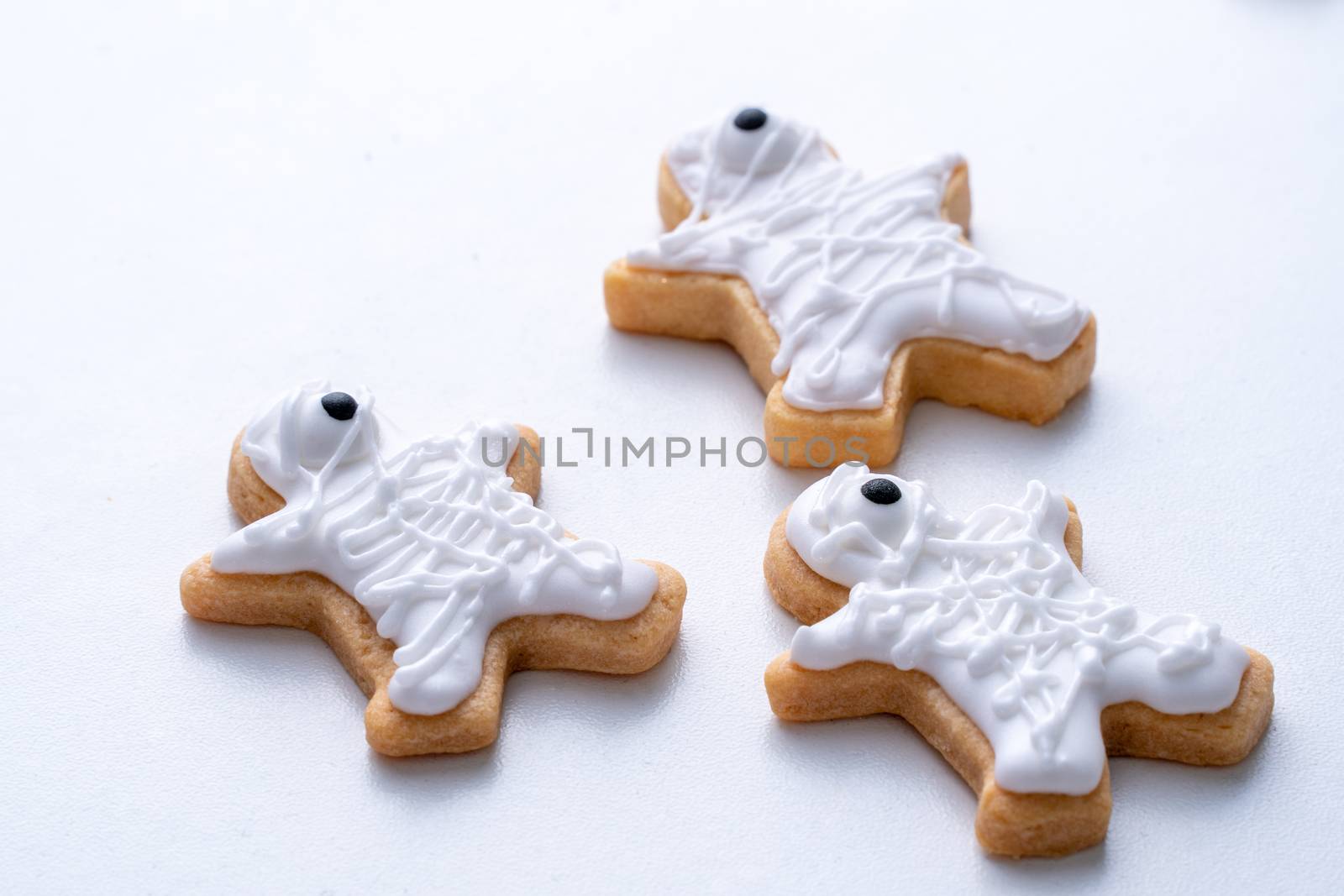 Close up of decorating cute Halloween gingerbread cookies with frosting icing cream topping bag.