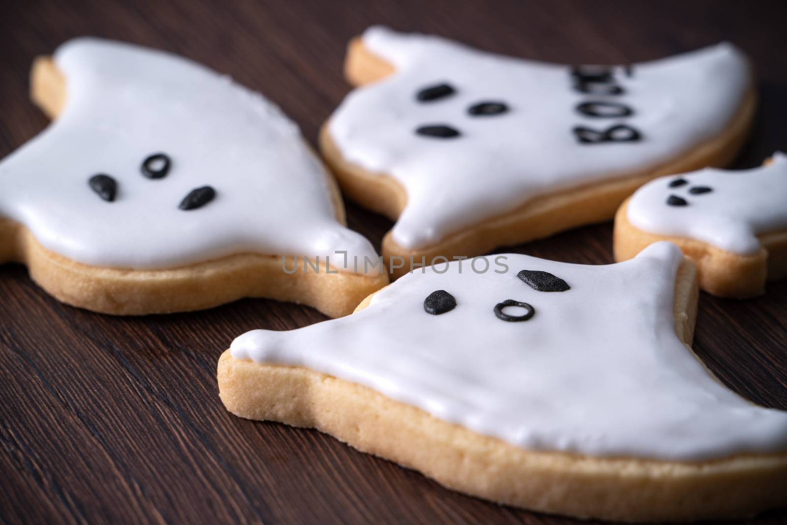 Close up of decorating cute Halloween ghost gingerbread cookies with frosting icing cream topping bag.