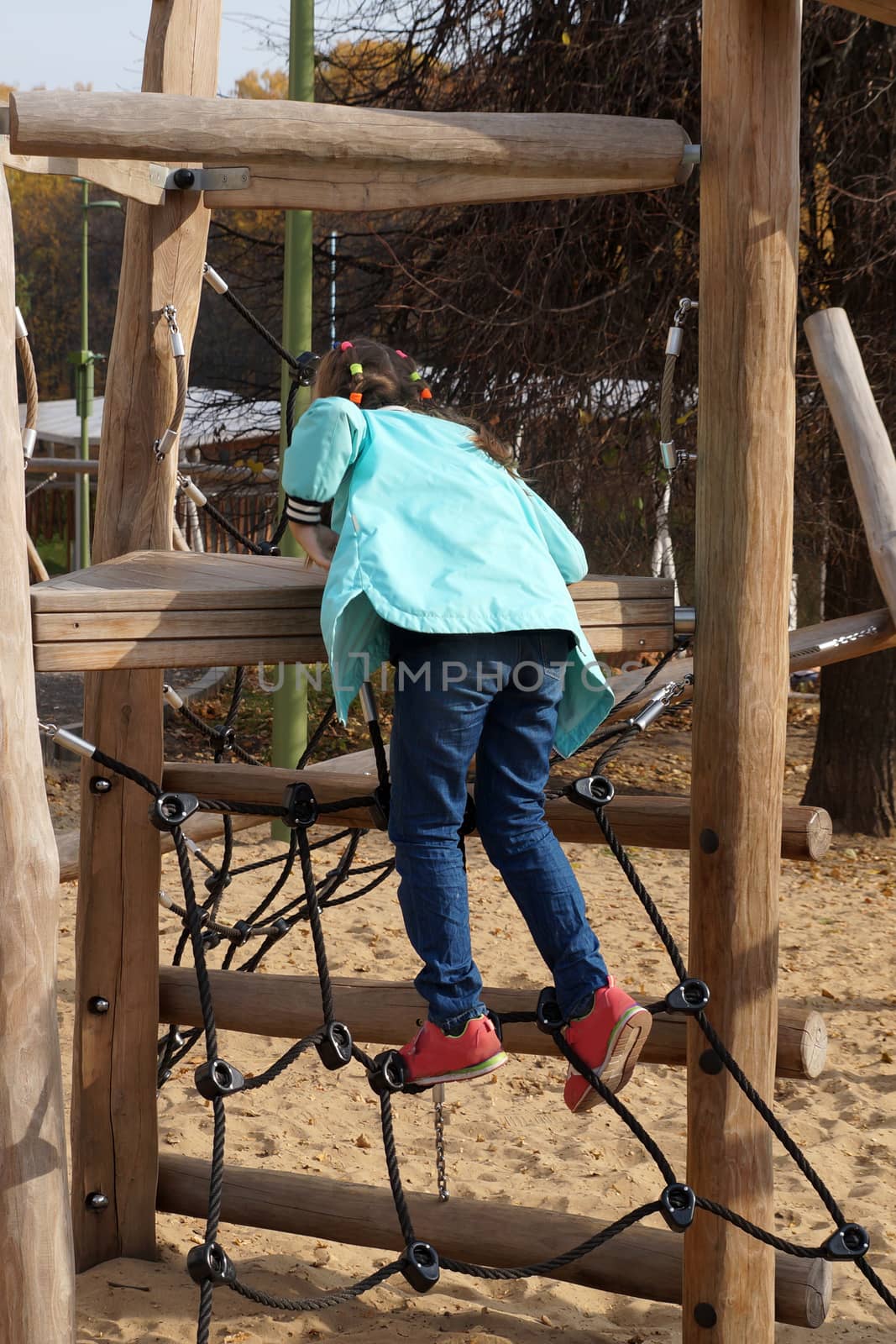 child girl climbing rope playground in the park.