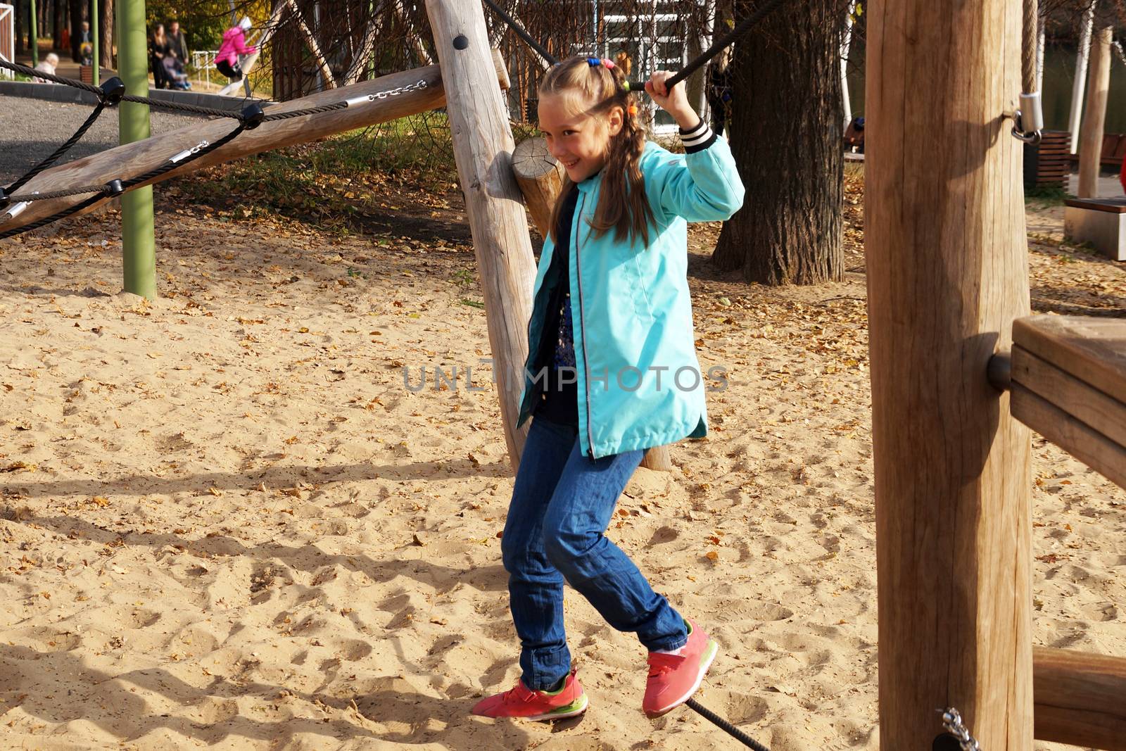 child girl walks the tightrope on the rope playground in the park