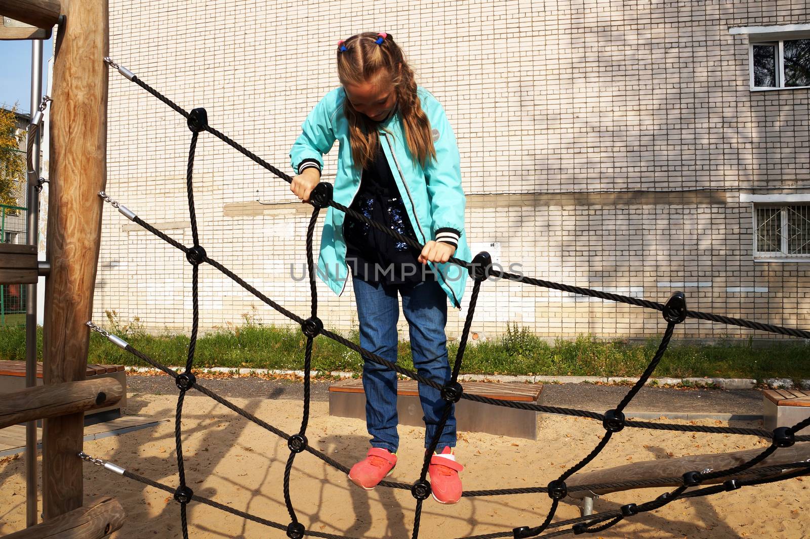 little girl climbing rope ladder on the playground in the park