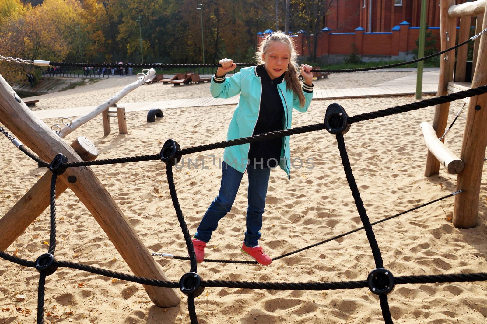 little girl climbing rope ladder on the playground by Annado