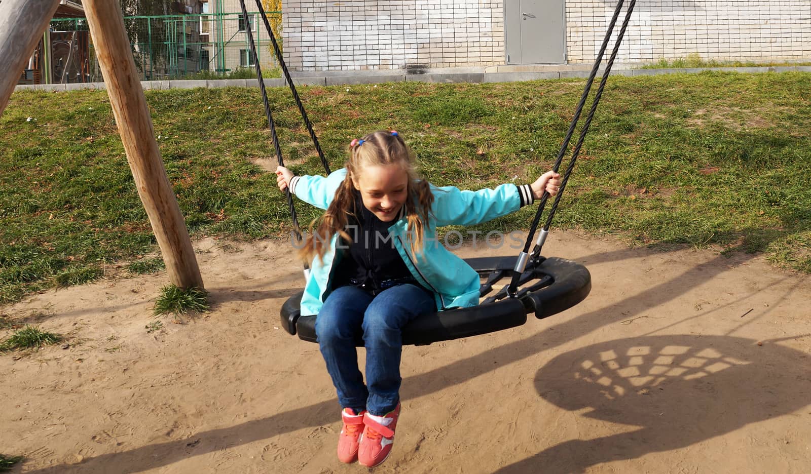 Child girl riding a swing and laughing by Annado