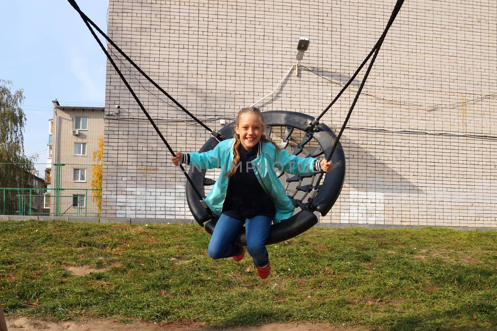 Child girl riding a swing and laughing by Annado