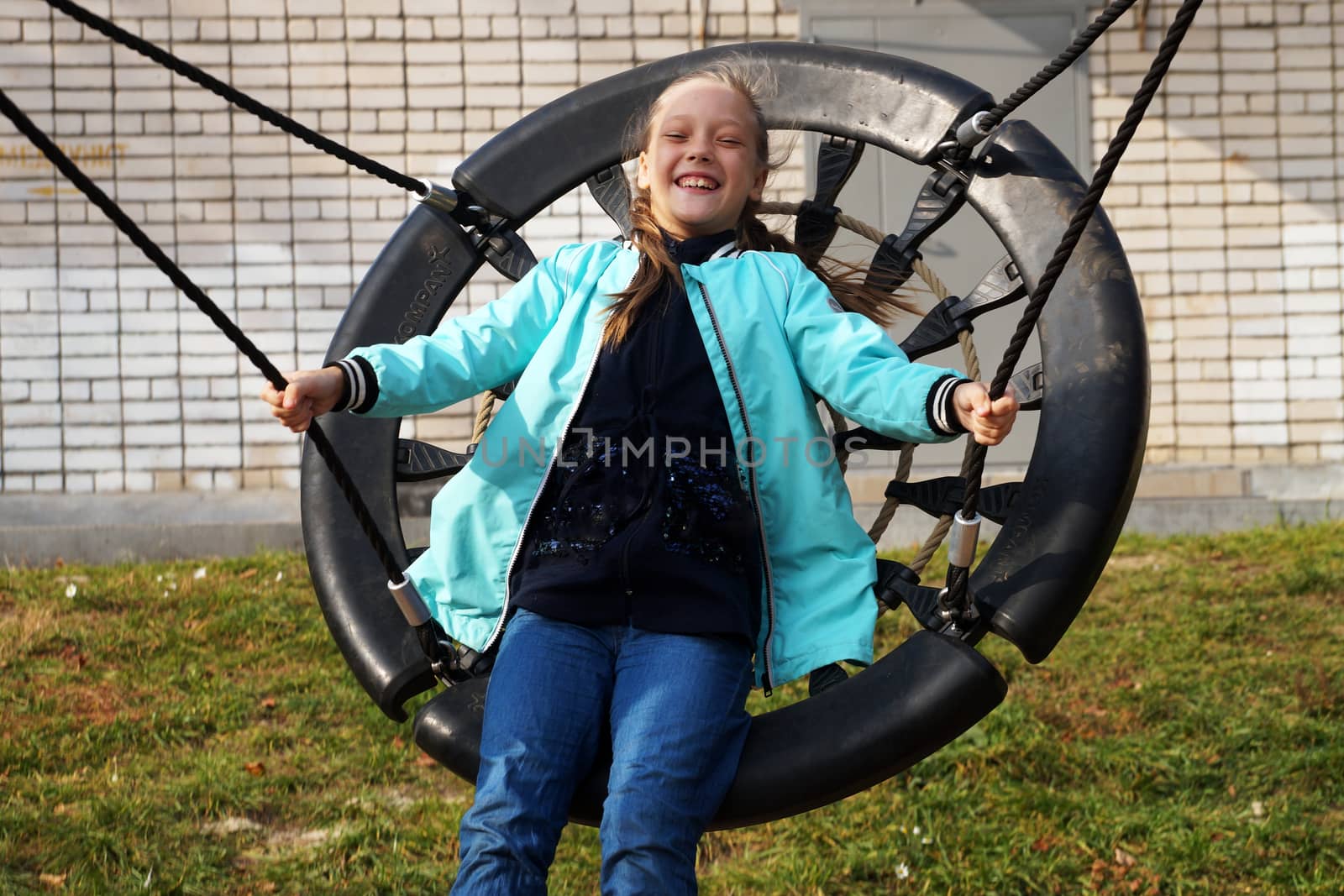 Child girl riding a swing and laughing by Annado