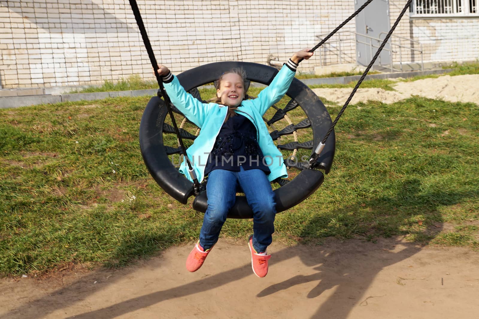 Child girl riding a swing and laughing by Annado