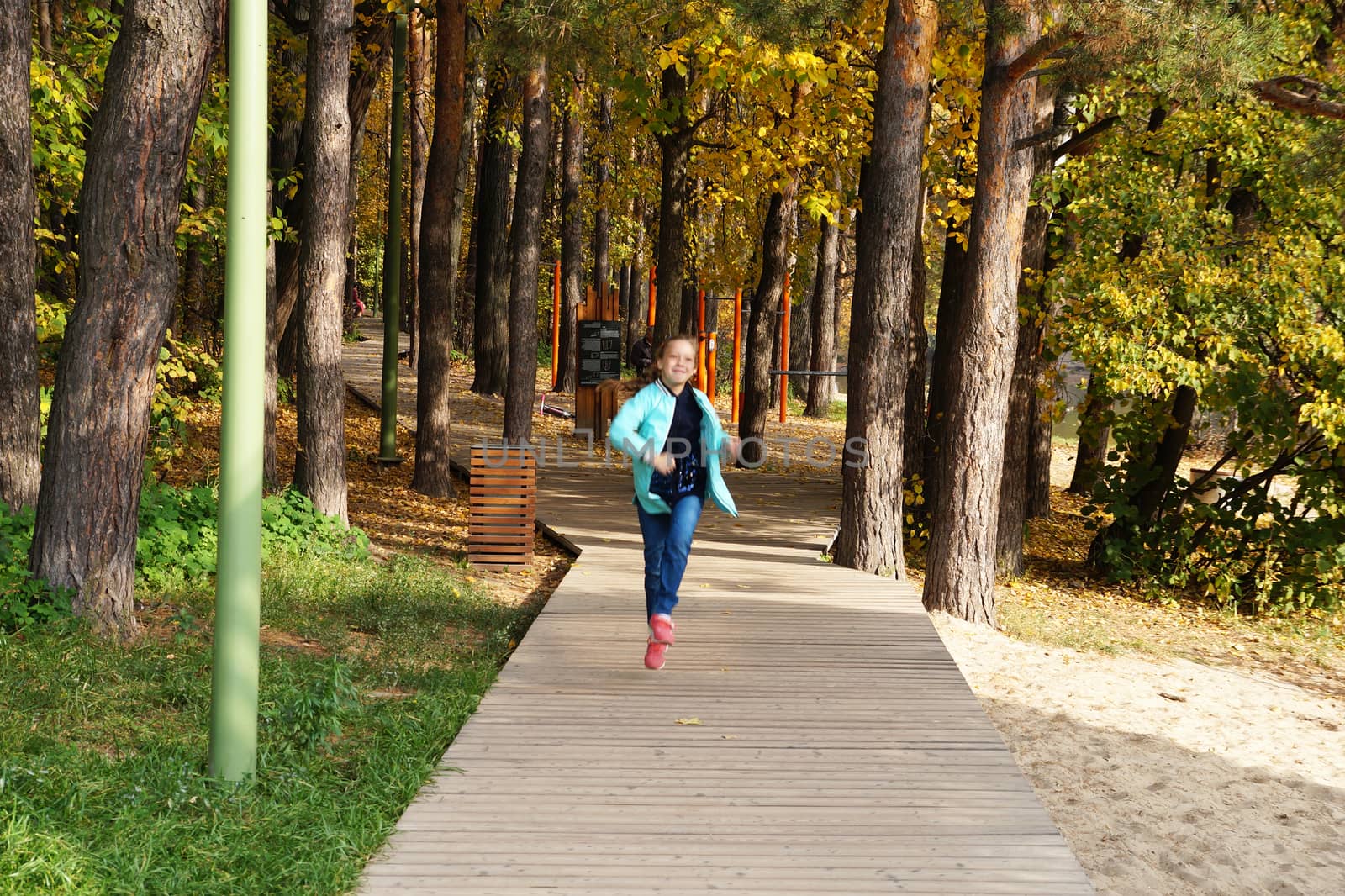 child girl running along the wooden path in the park by Annado