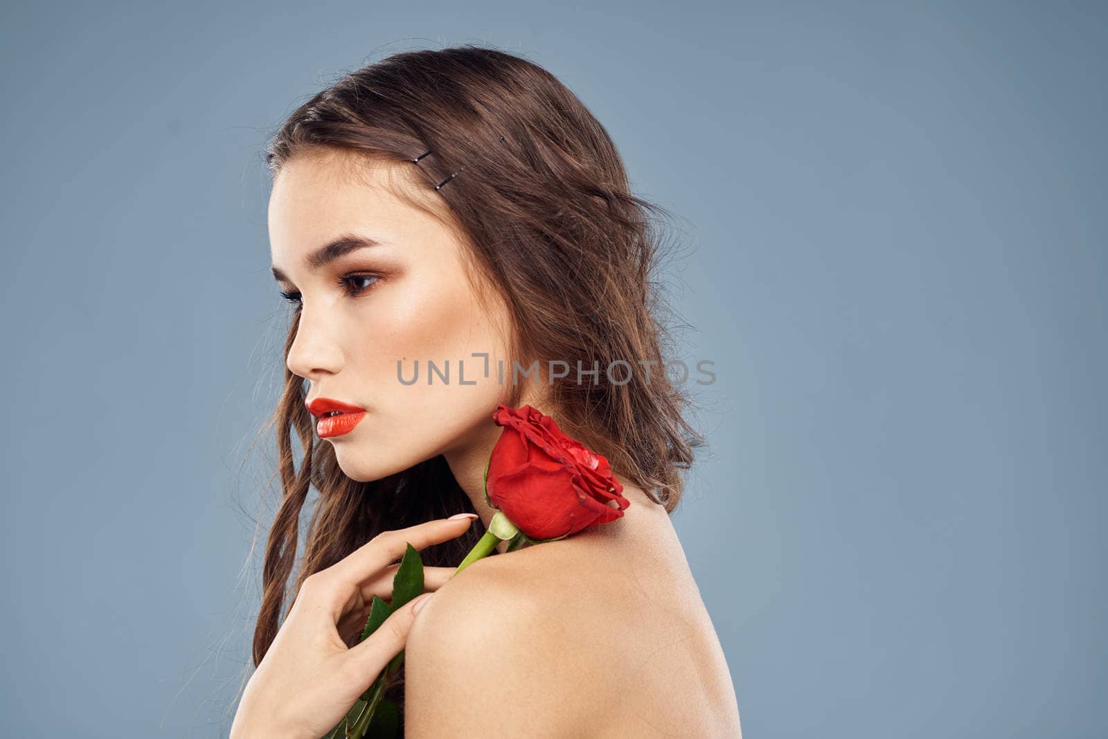 woman with a rose in her hands naked shoulders evening makeup red lips. High quality photo