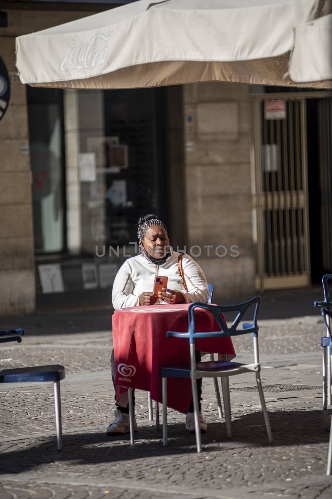 terni,italy october 21 2020:black woman sitting at a table in an outdoor cafe