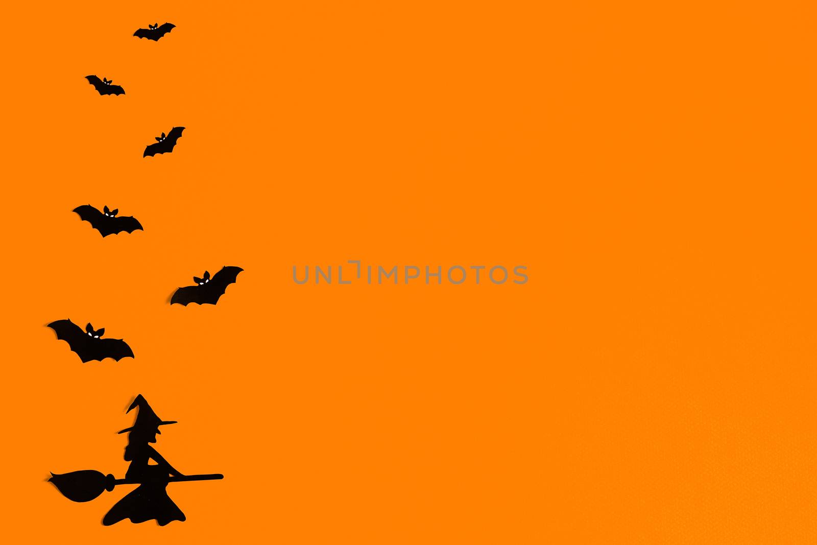 Silhouettes of a flock of bats and a witch flying on a broom made of black paper on an orange background. Halloween greeting template with copy space. Flat lay for your design. ready-made template by Pirlik