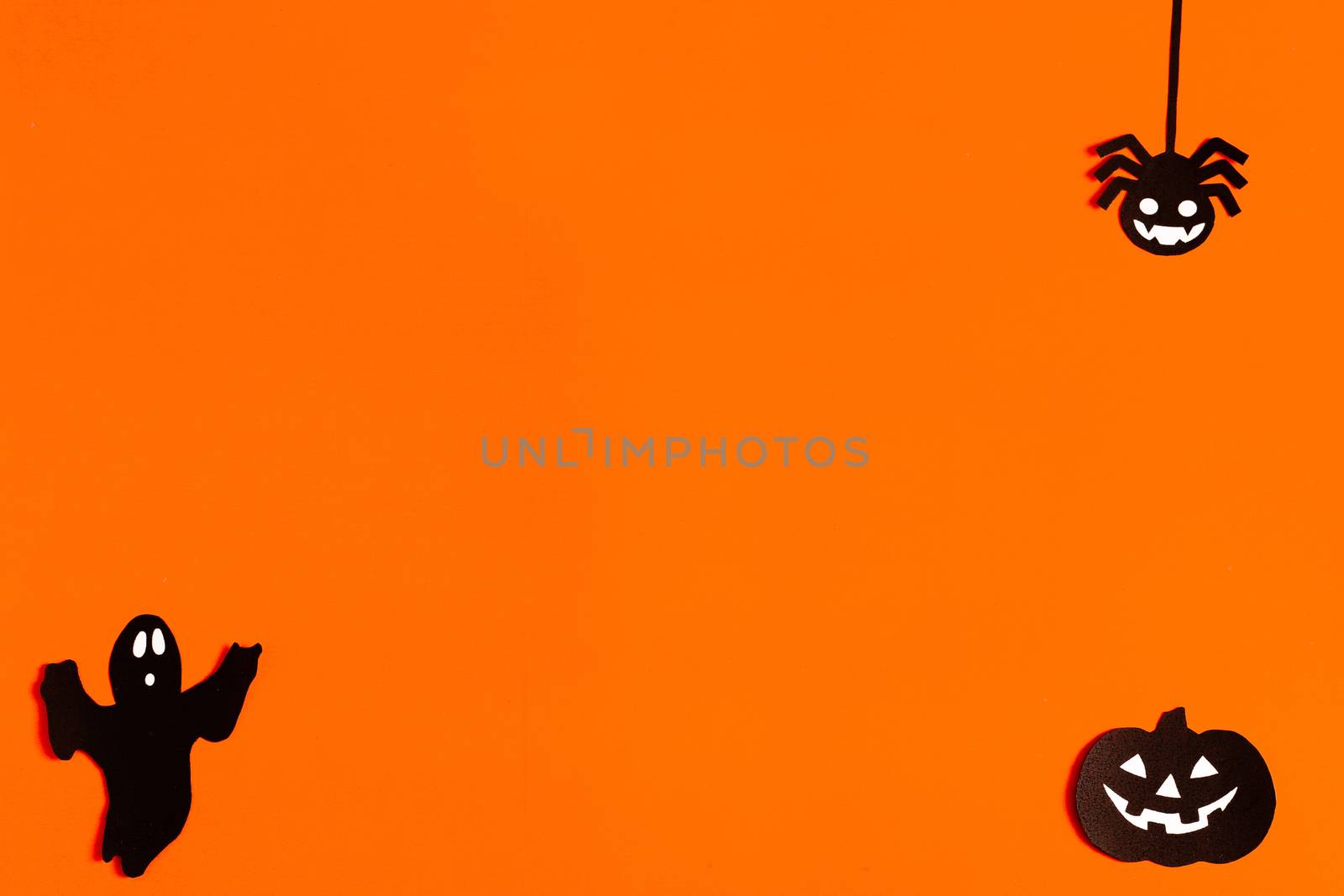 silhouettes of a Ghost, spider and pumpkin made of black paper on an orange background, Halloween concept, ready-made layout with space for text, copy space. Flat lay for your design.