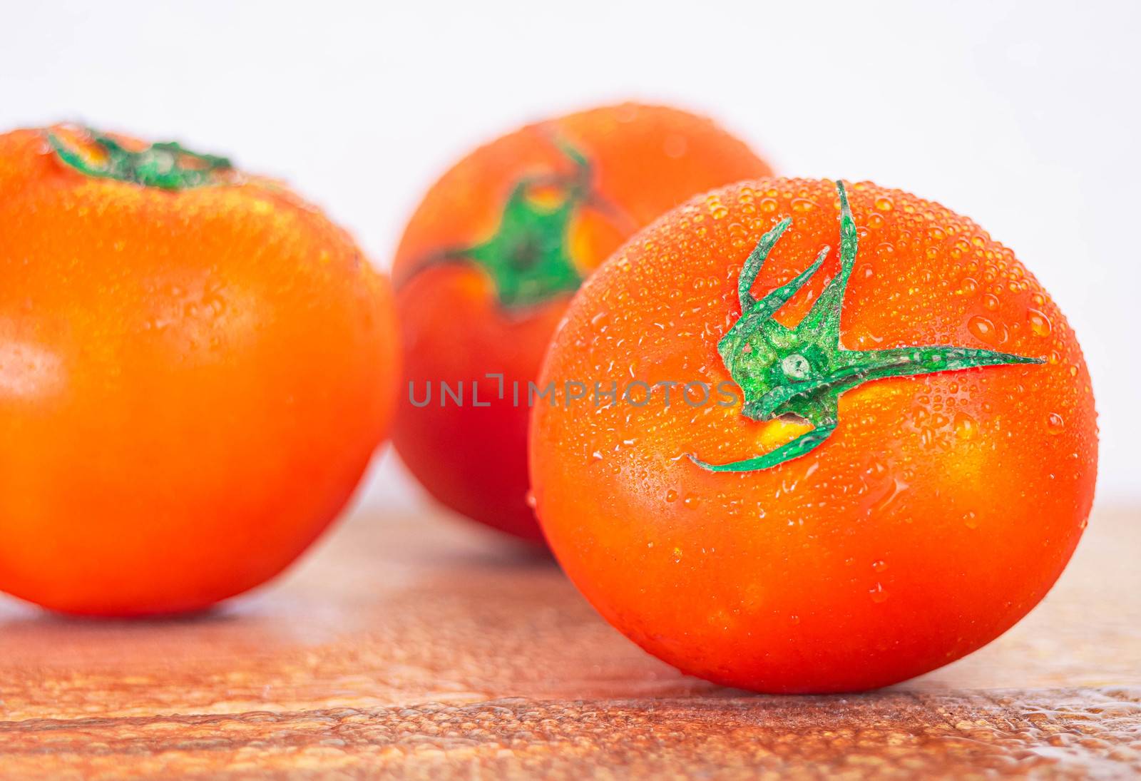 Red ripe tomatoes with water spray to freshness after harvesting on wooden background.