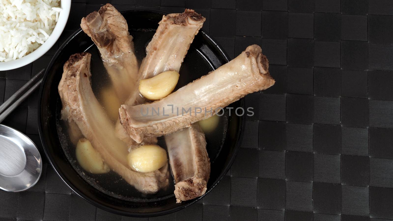 Bak kut teh or pork ribs soup which made from many ingredients such as big garlic, white pepper and many spices. Very popular traditional authentic menu dish in Singapore and Malaysia. Served hot with rice bowl