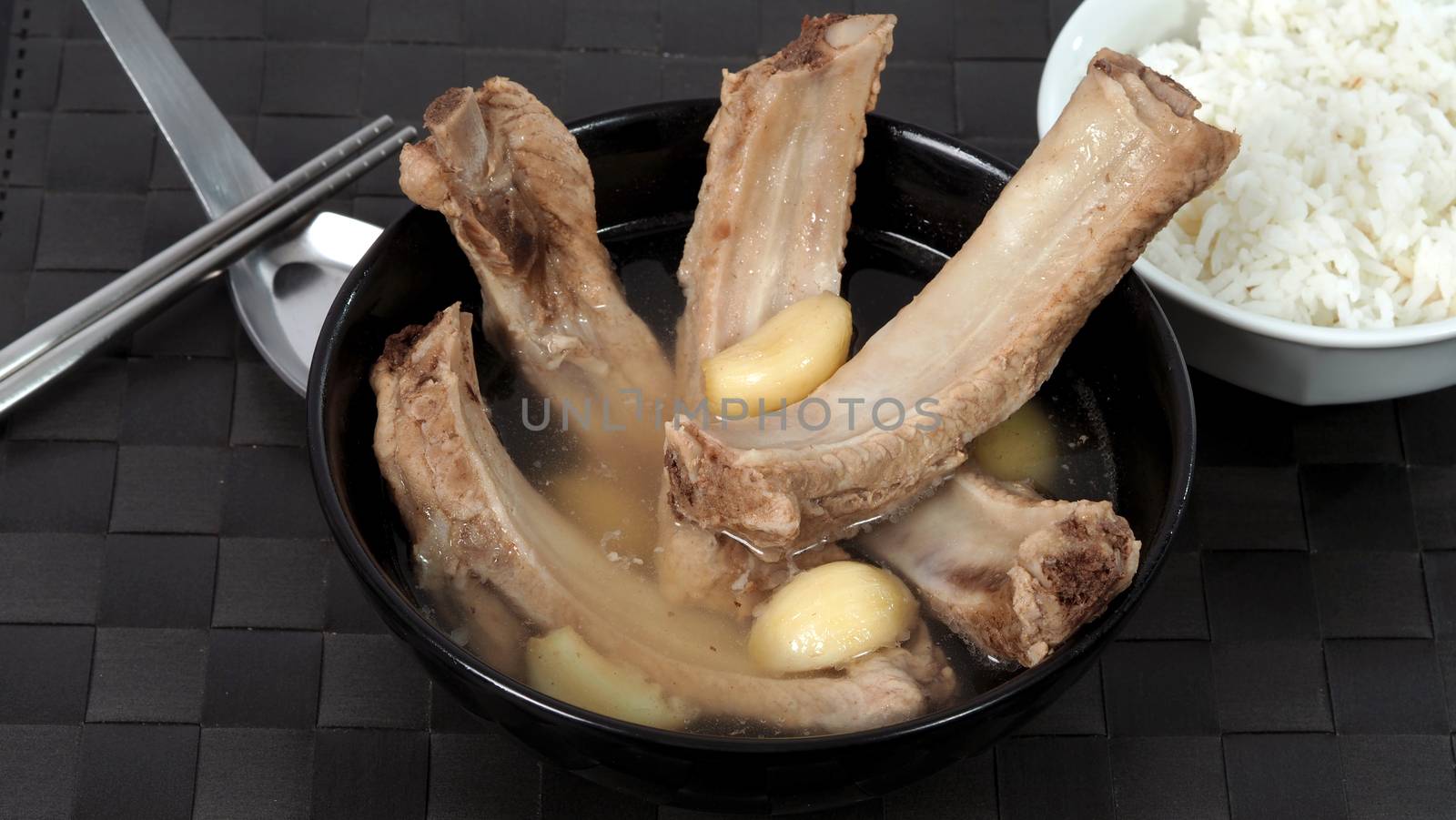 Bak kut teh or pork ribs soup which made from many ingredients such as big garlic, white pepper and many spices. Very popular traditional authentic menu dish in Singapore and Malaysia. Served hot with rice bowl