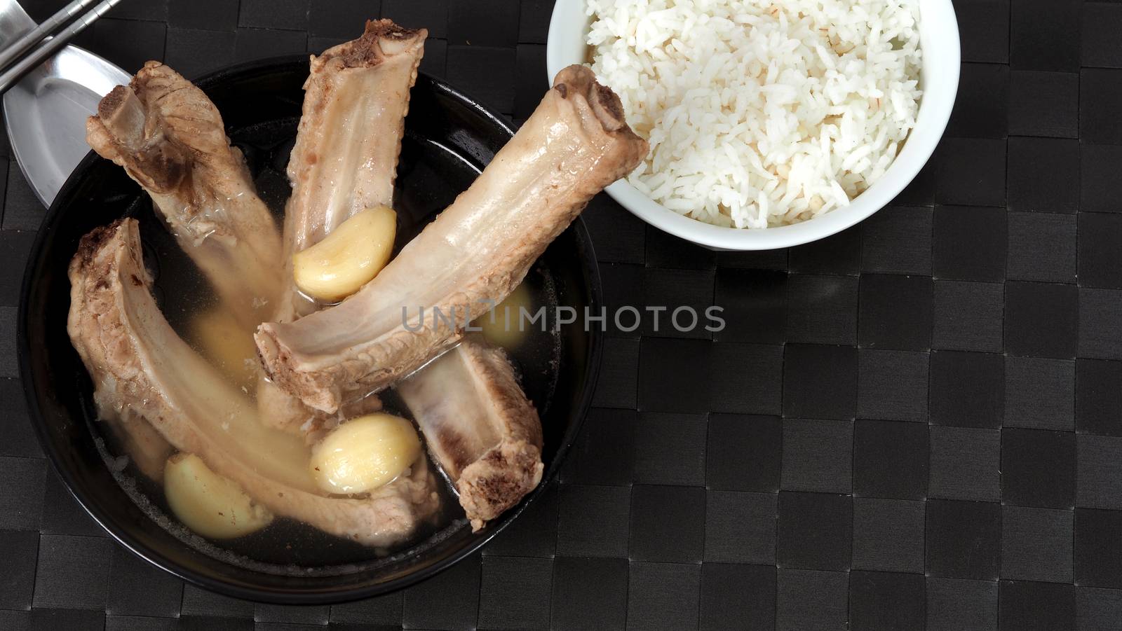 Bak kut teh or pork ribs soup which made from many ingredients such as big garlic, white pepper and many spices. Very popular traditional authentic menu dish in Singapore and Malaysia. Served hot with rice bowl