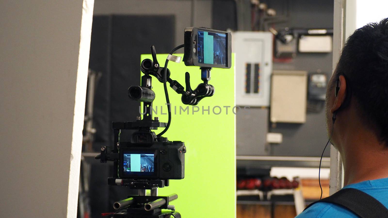 Behind video camera and green screen for movie or film production and equipment in the big studio.