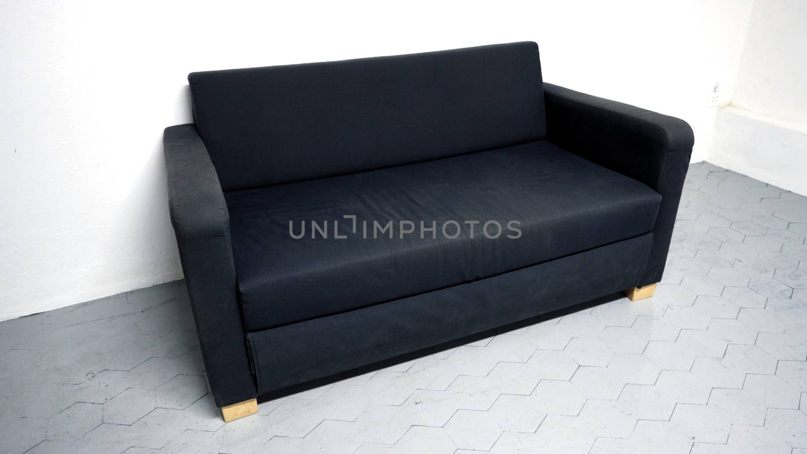 Black color sofa that made from wood and fabric in the white room and grey floor and no people.