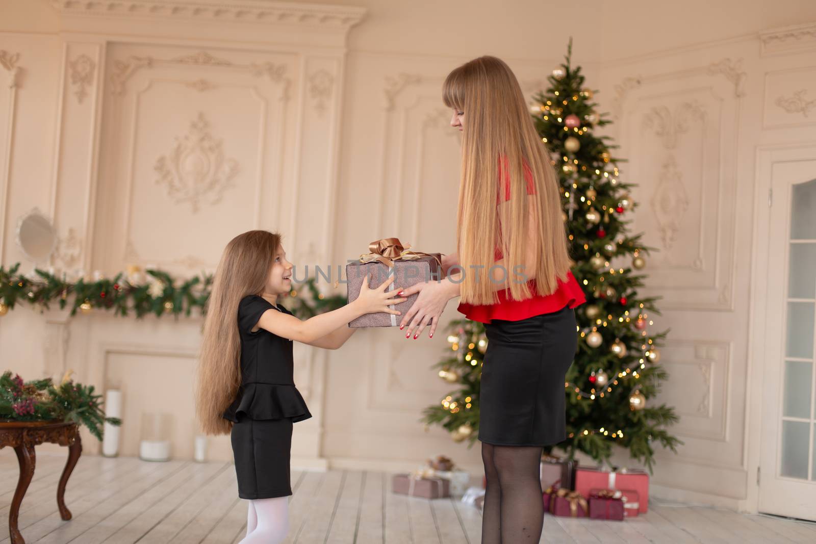 Little girl gives her mom a box with a Christmas present.