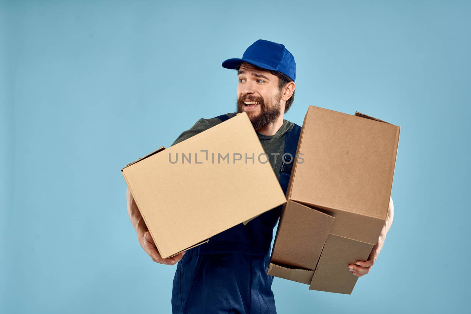 working man boxes in hands delivery service packaging lifestyle blue background. High quality photo