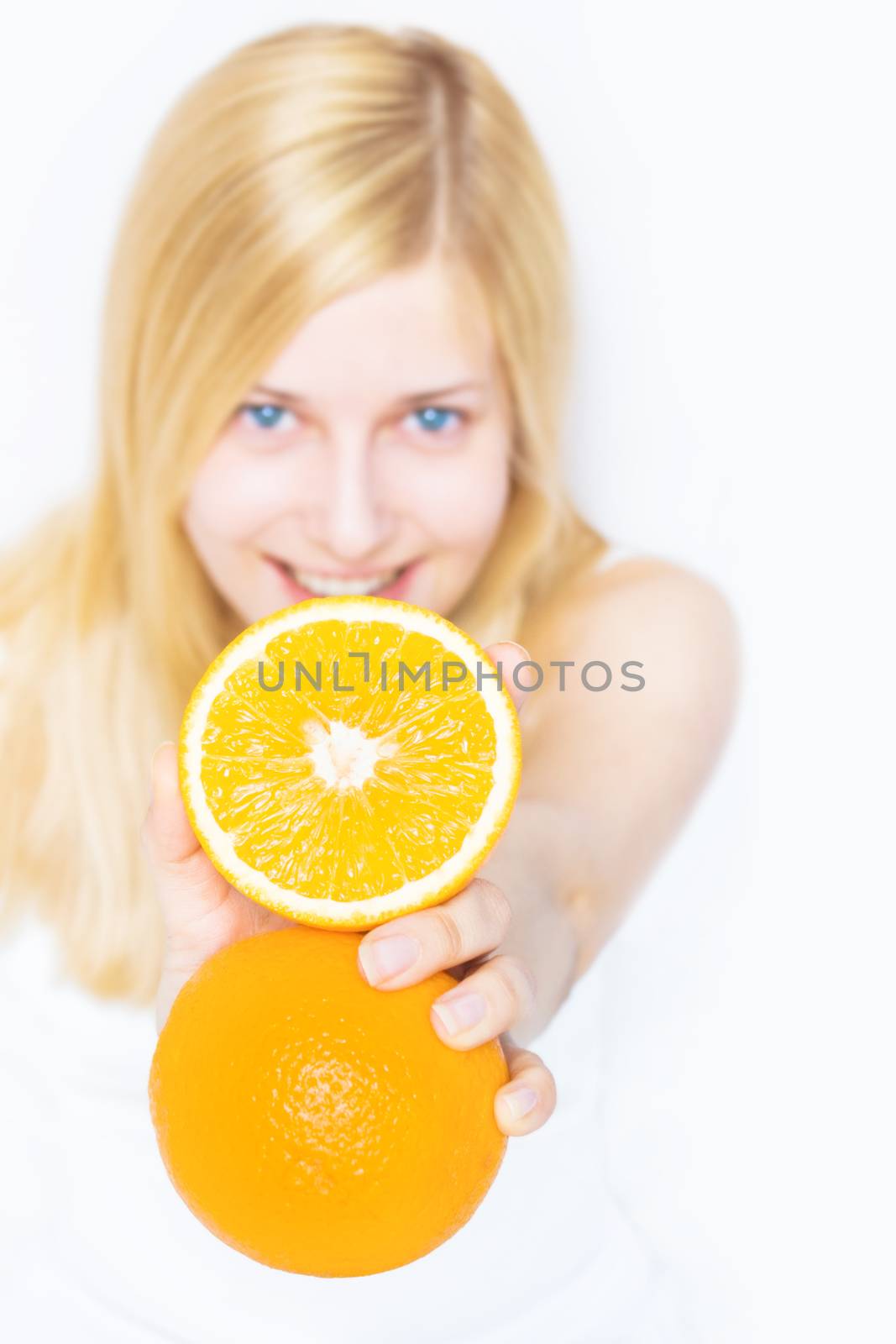 Young blonde holding orange fruit and smiling, healthy eating an by Anneleven