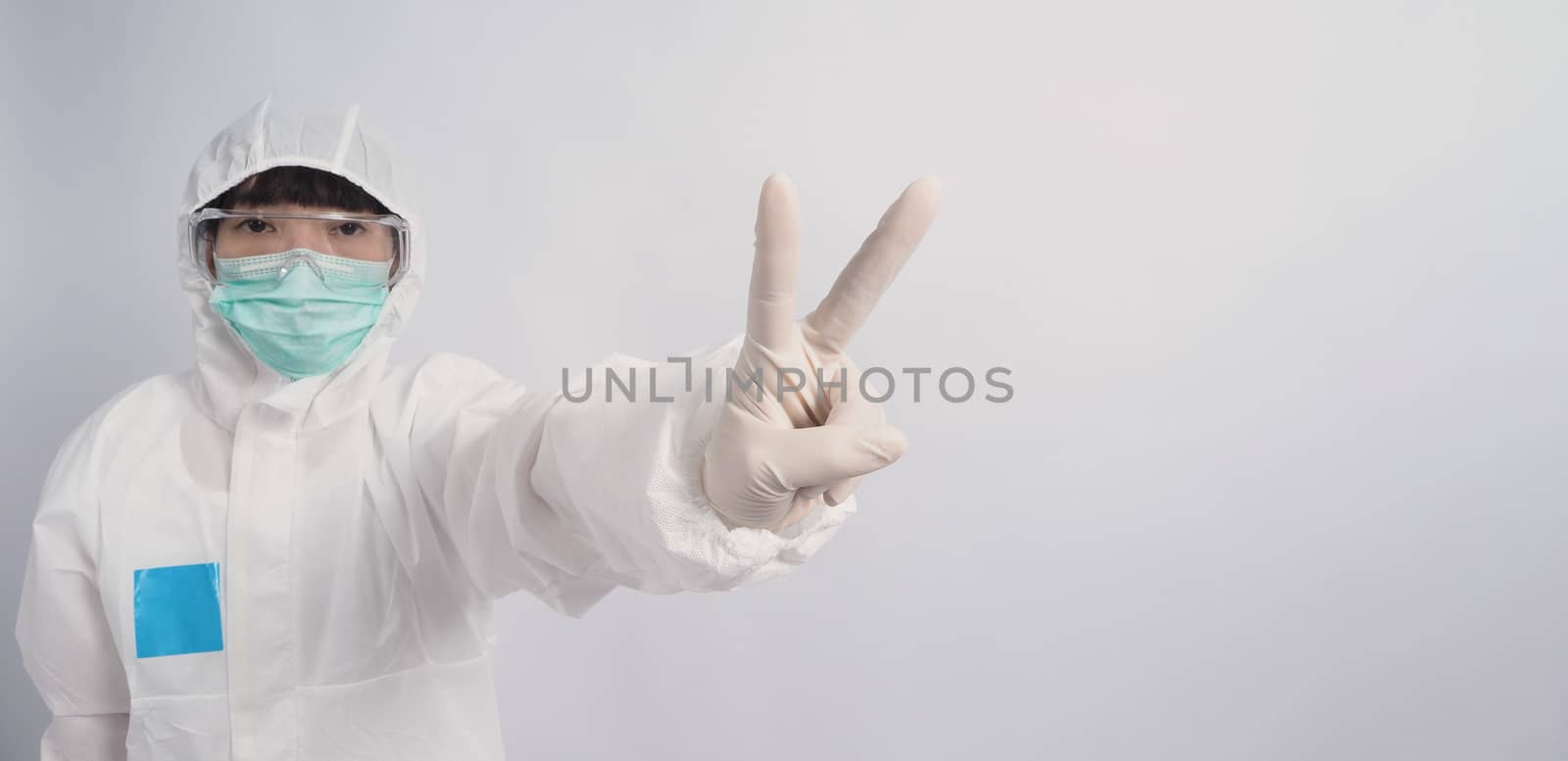 Asia woman doctor in PPE suit or Personal Protective Equipment uniform and wearing medical face mask, rubber gloves and goggles for protect coronavirus pandemic. Studio shot with copy space.