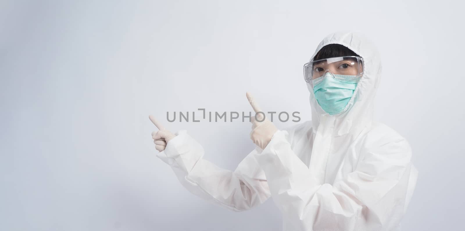 Asia woman doctor in PPE suit or Personal Protective Equipment uniform and wearing medical face mask, rubber gloves and goggles for protect coronavirus pandemic. Studio shot with copy space.