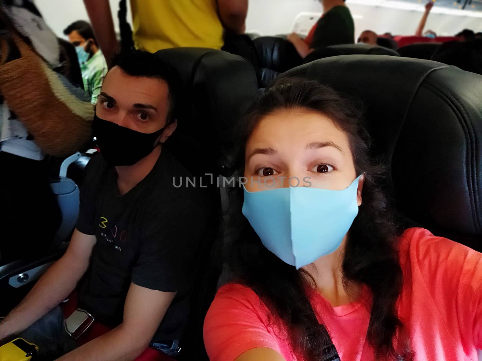 couple of travelers wearing masks on their faces in the cabin. Flights under the new rules of the coronavirus pandemic. by Try_my_best