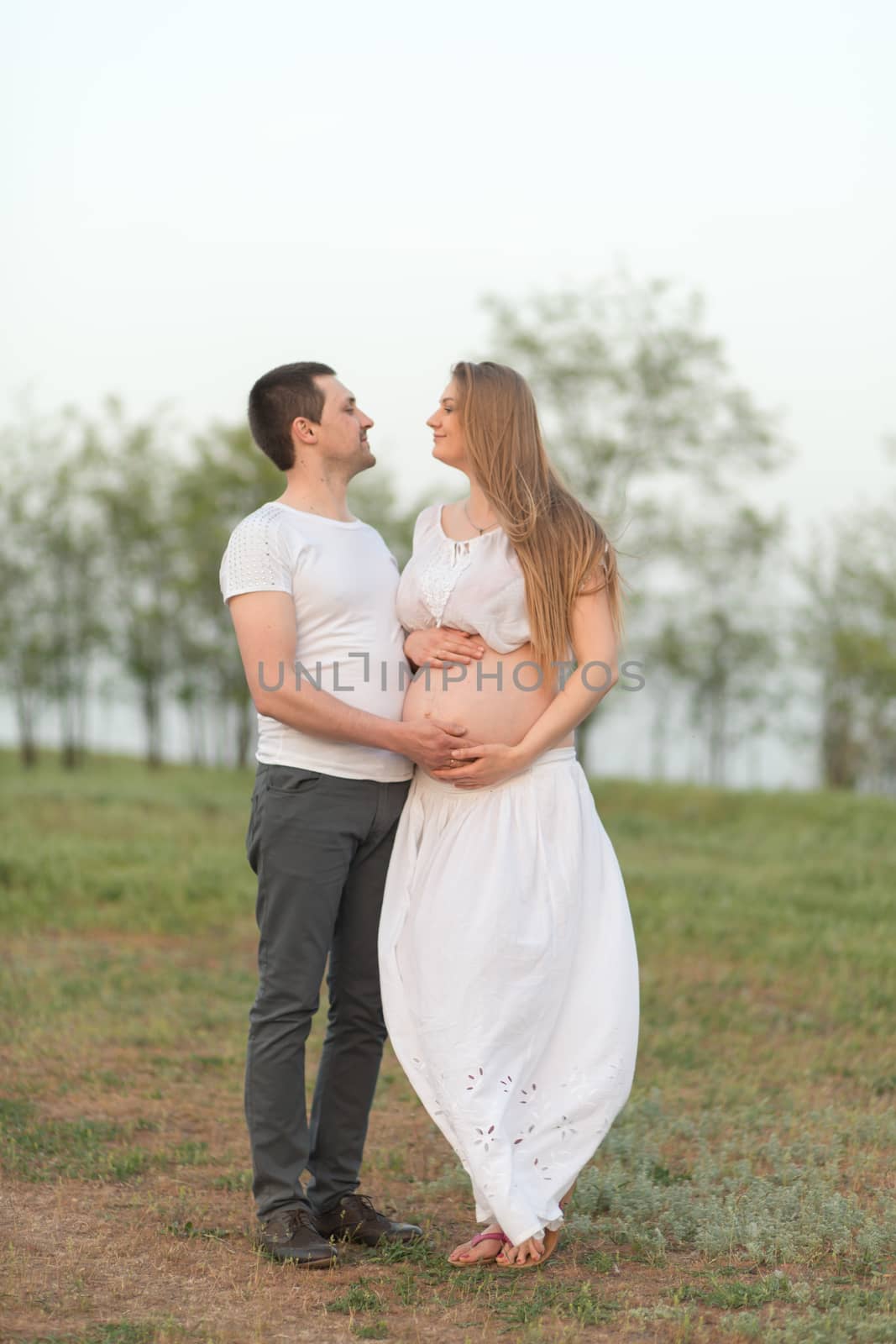 Happy moments of pregnancy. A loving husband with his pregnant wife in the fresh air away from the city.