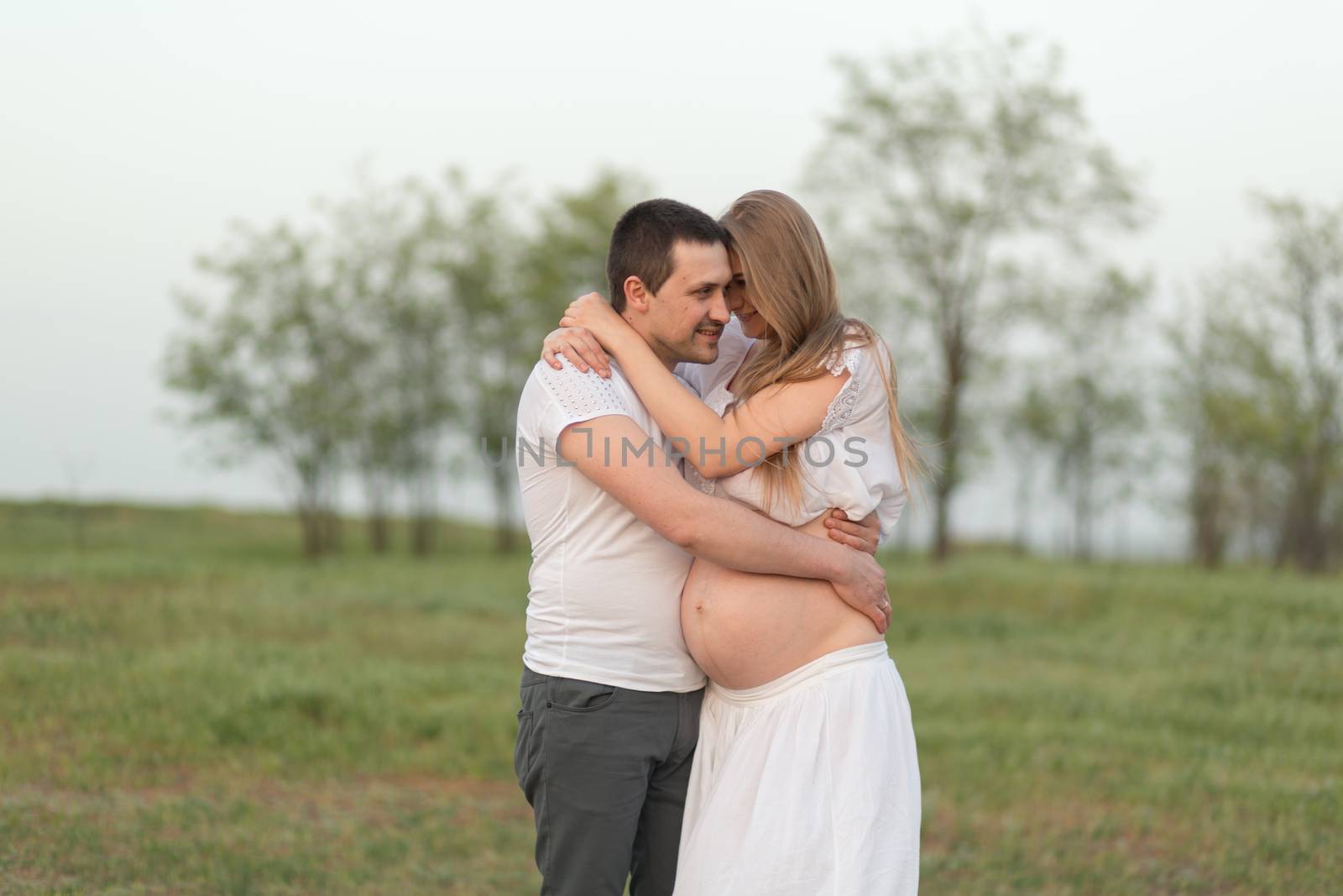 Happy moments of pregnancy. A loving husband with his pregnant wife in the fresh air away from the city.