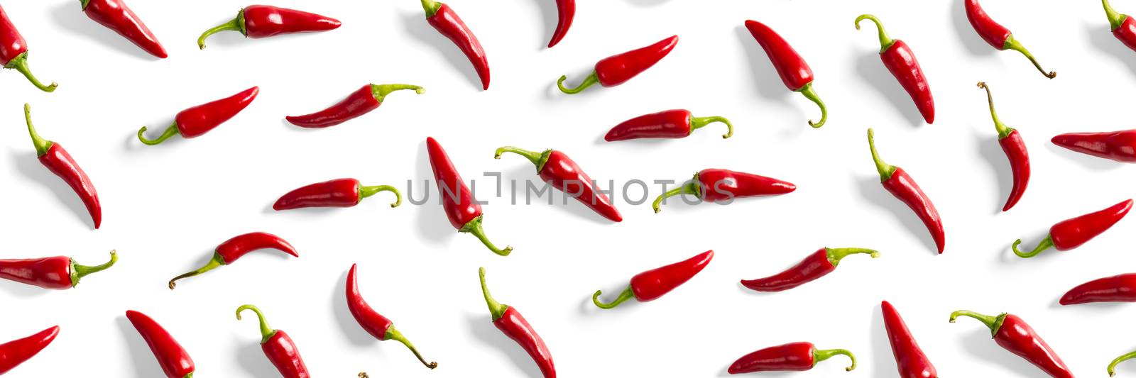 Creative background made of red chili or chilli on white backdrop. Minimal food backgroud. Red hot chilli peppers background. by PhotoTime