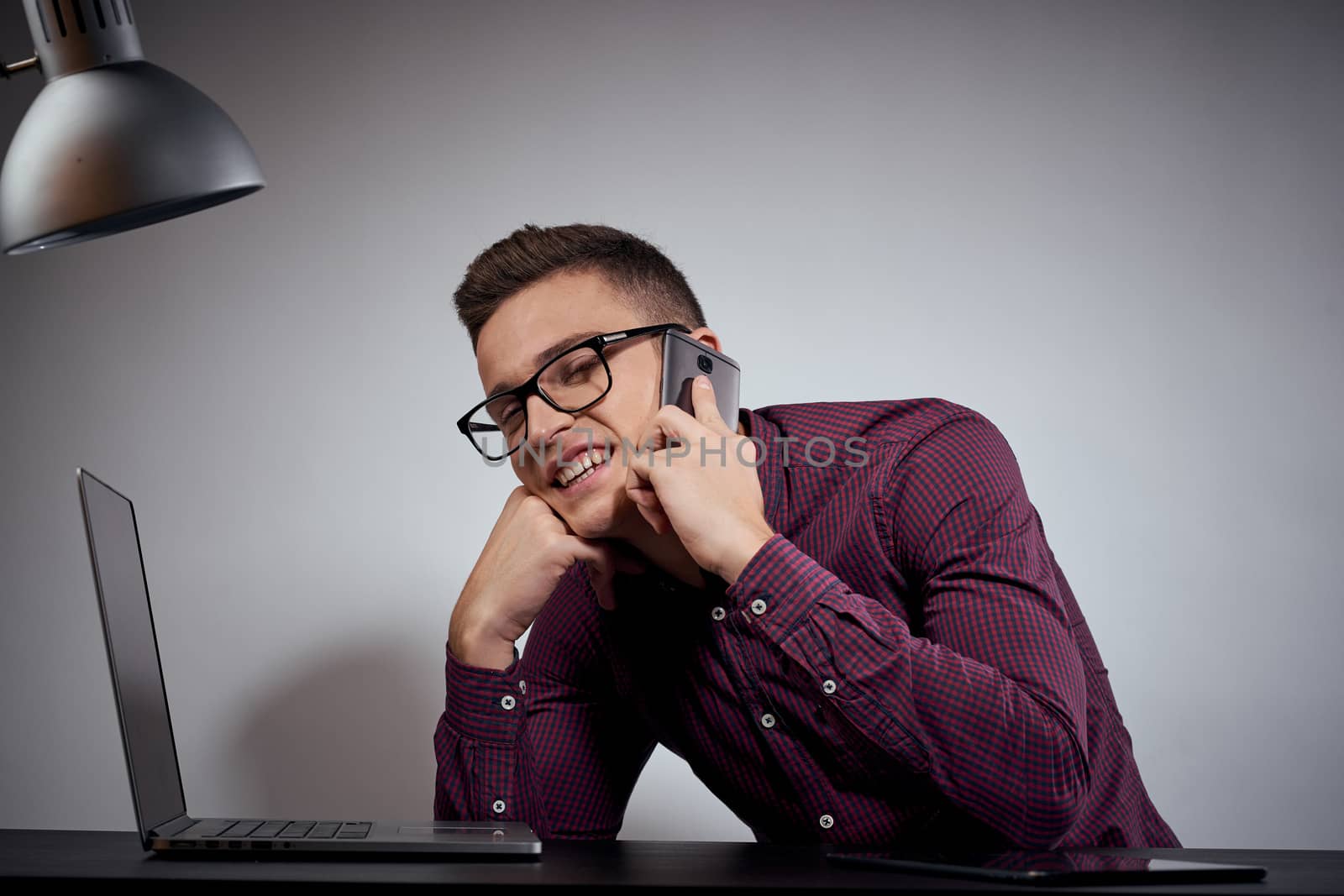 businessman in glasses and a shirt sits at a table with open laptops Coffee Space mobile phone. High quality photo