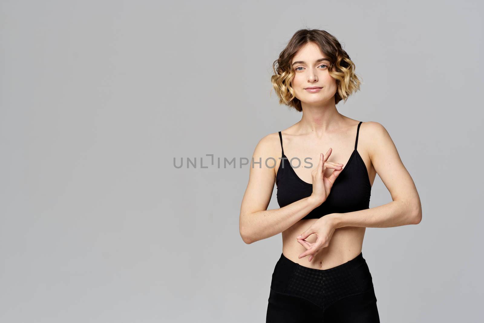 woman gesturing with her hands slim figure meditation sport gray background. High quality photo