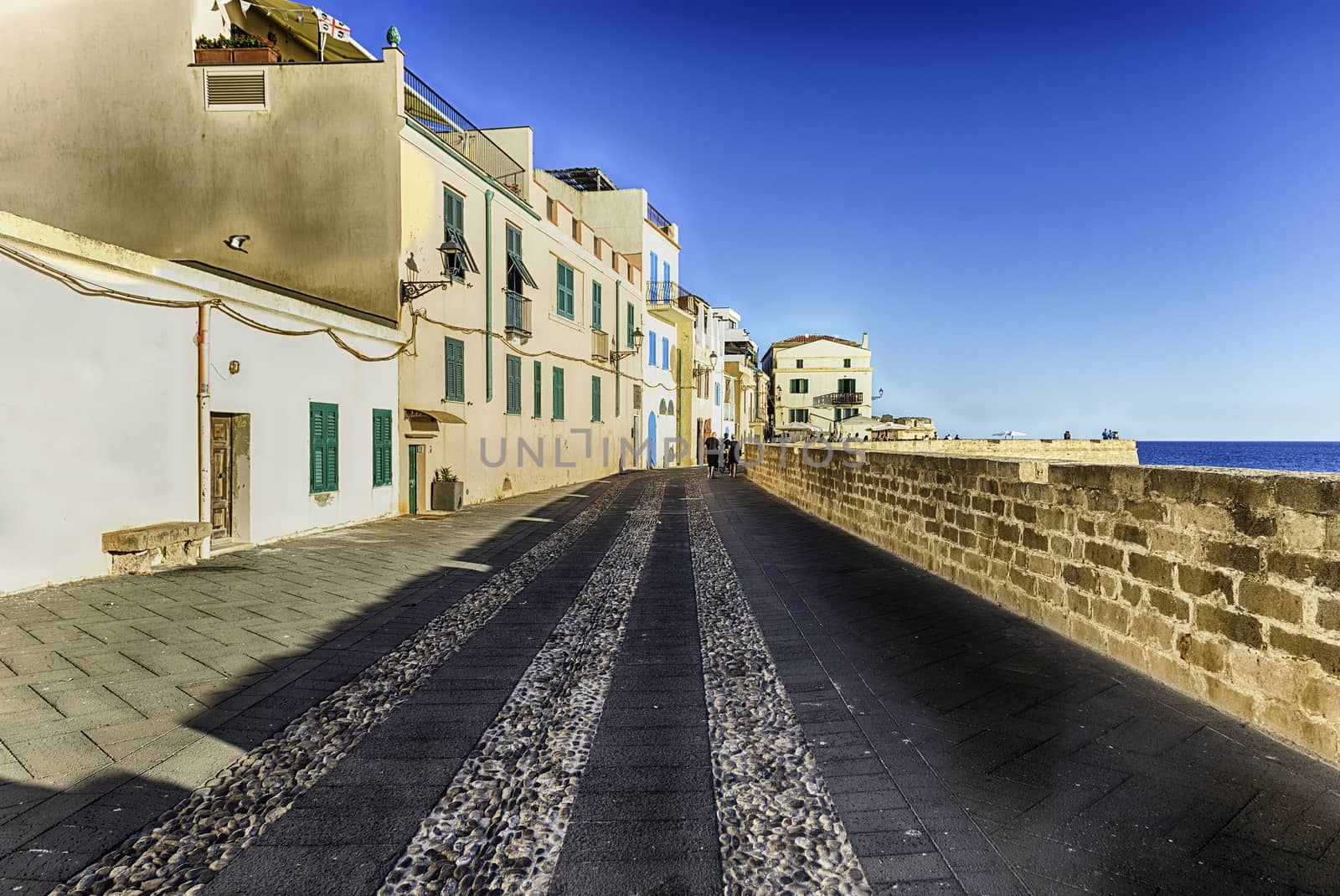Walking at sunset on the historic ramparts, one of the main sightseeing in Alghero, famous center and holiday resort in northwestern Sardinia, Italy