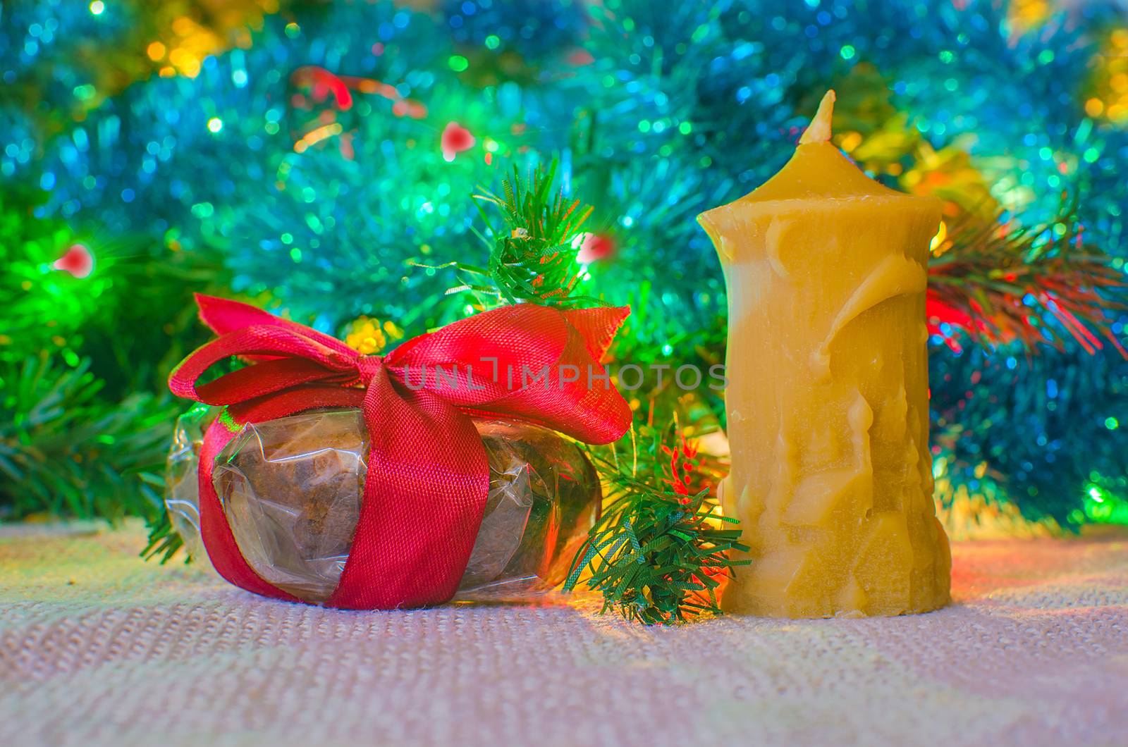 Celebration present and candle on blurred light backdrop. Festive decoration on lighted background