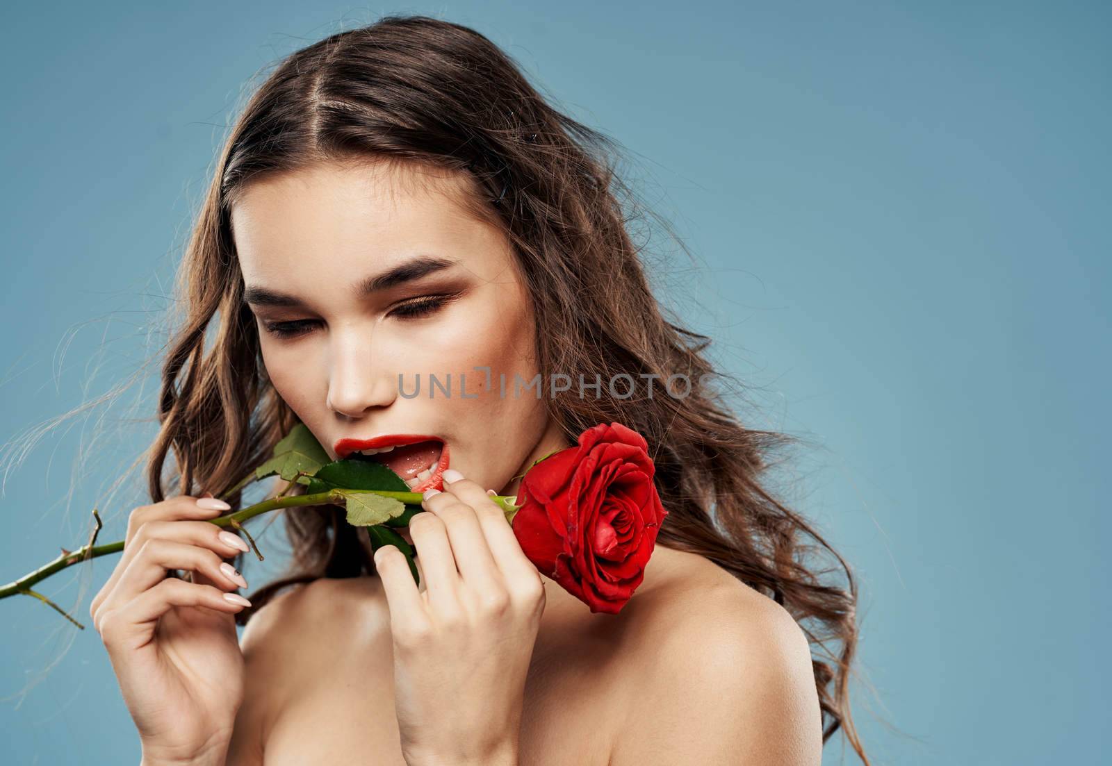 Passionate woman with red rose eye shadow on eyelids blue background cropped view. High quality photo