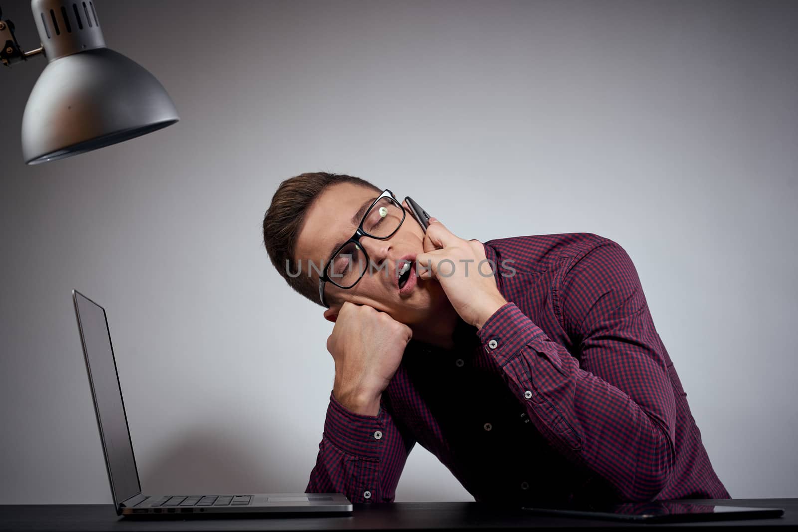 businessman in glasses and a shirt sits at a table with open laptops Coffee Space mobile phone. High quality photo