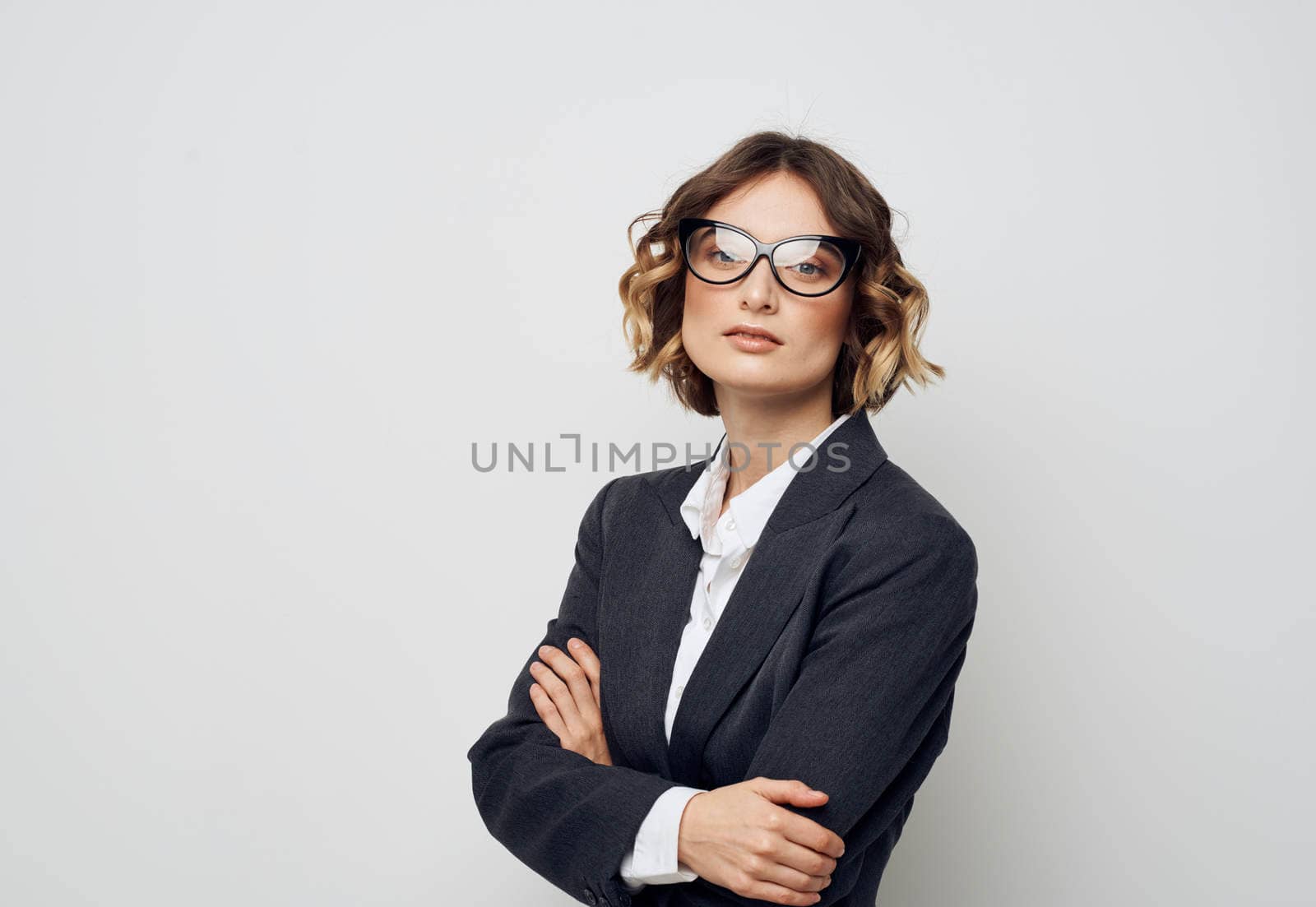 A business woman in glasses and in a suit on a light background crossed her arms over her chest. High quality photo