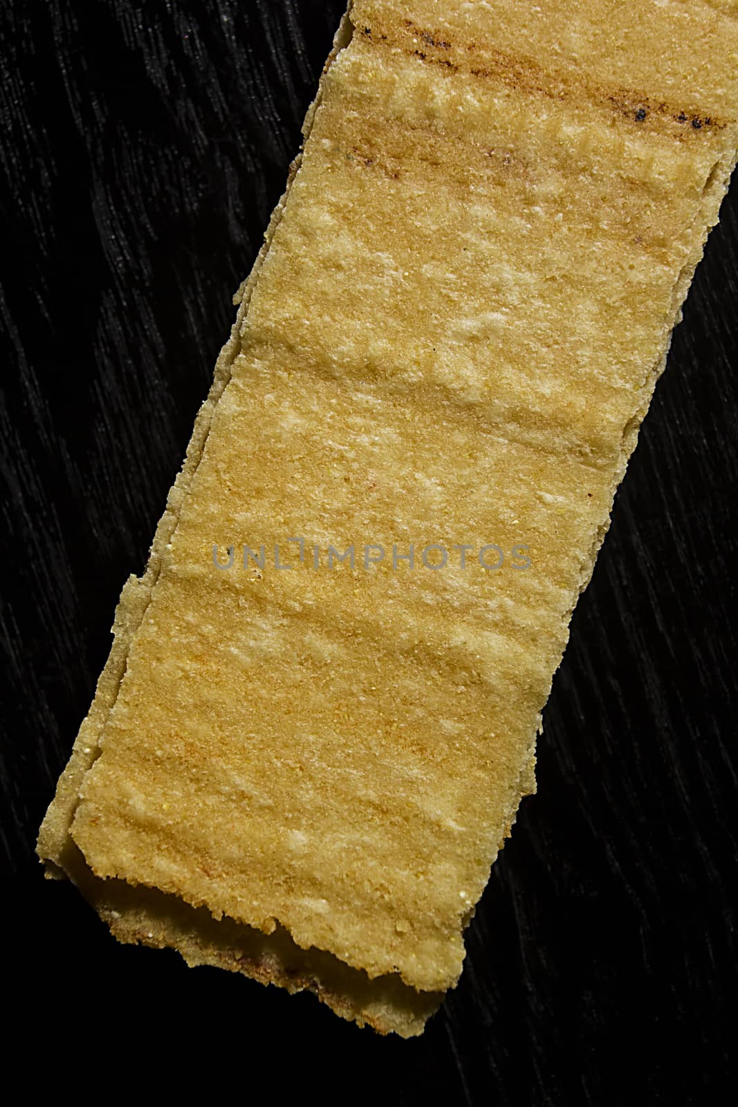 Rectangular potato chips on black wooden background