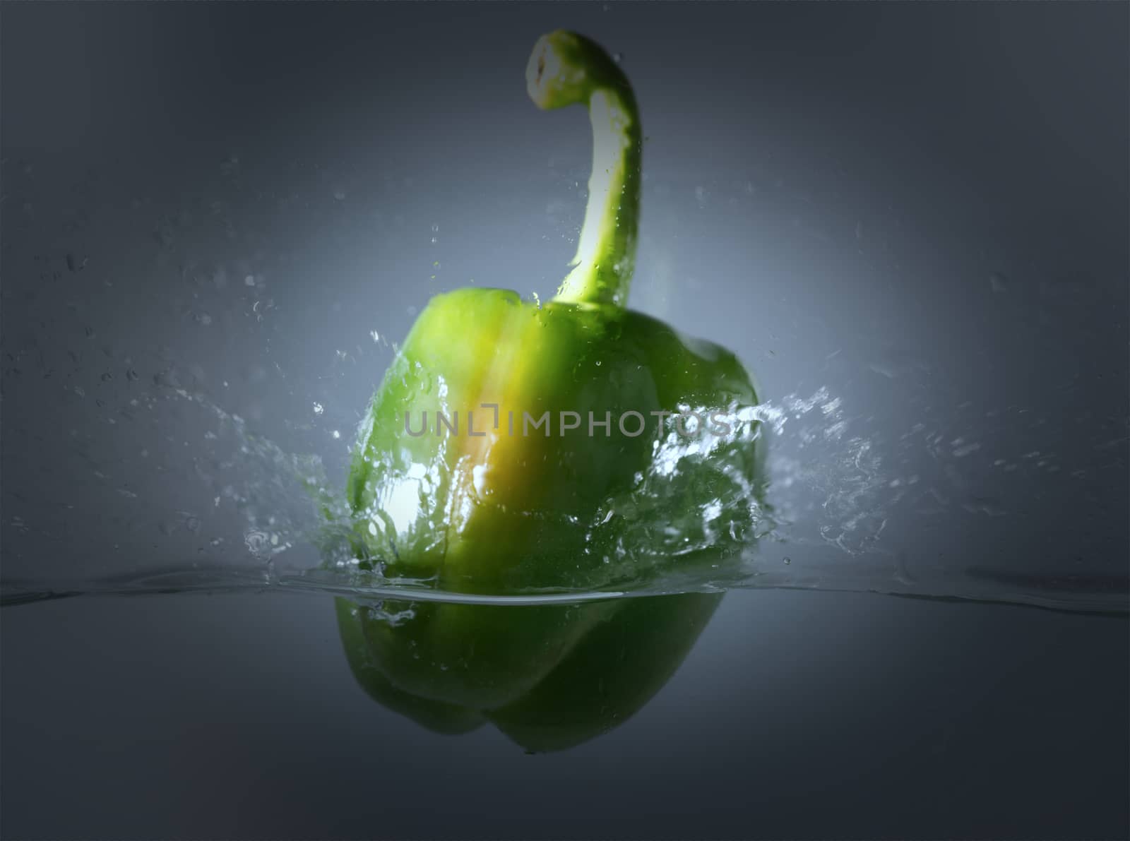 Vintage green bell peppers thrown into the water with a splash of water.