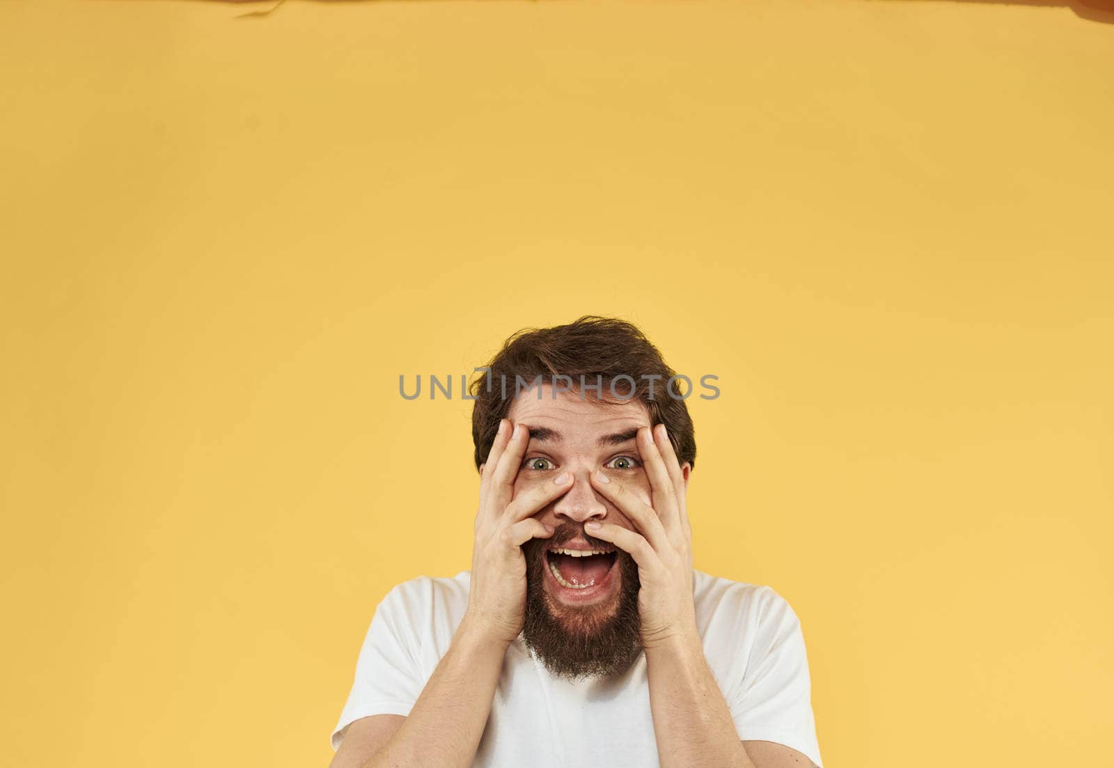 Upset man holds his hands near his face on a yellow background. High quality photo