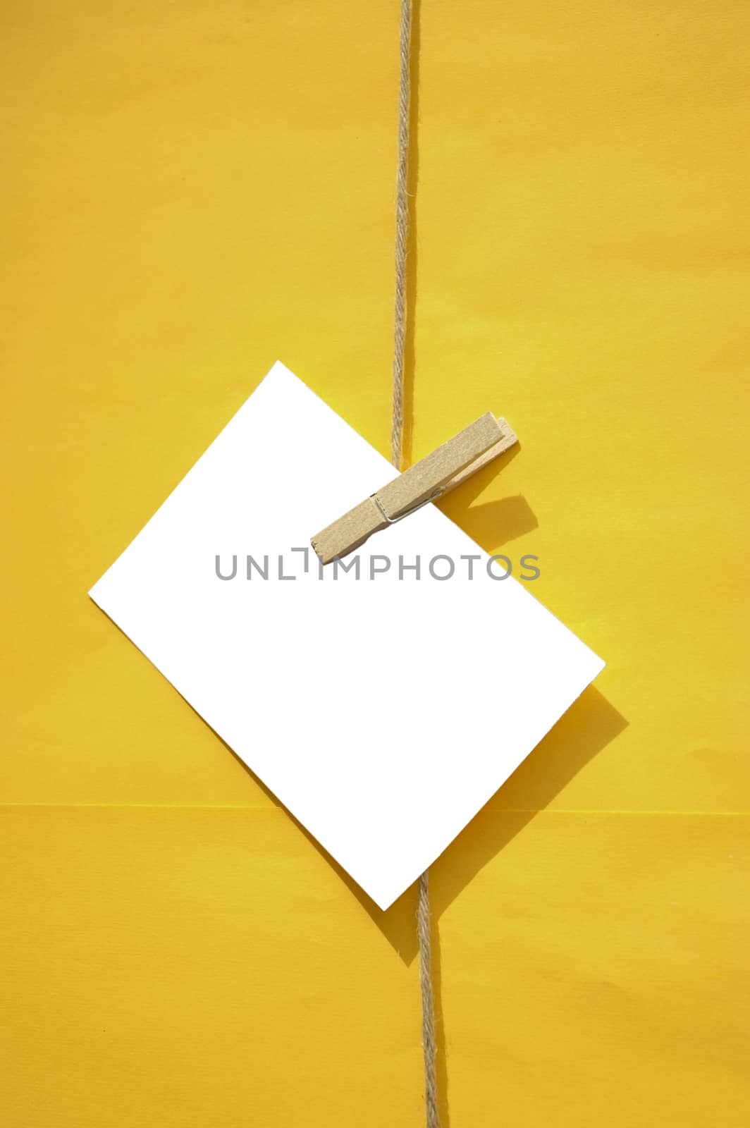 White paper note with wooden clip hang in front of yellow wall by eyeofpaul