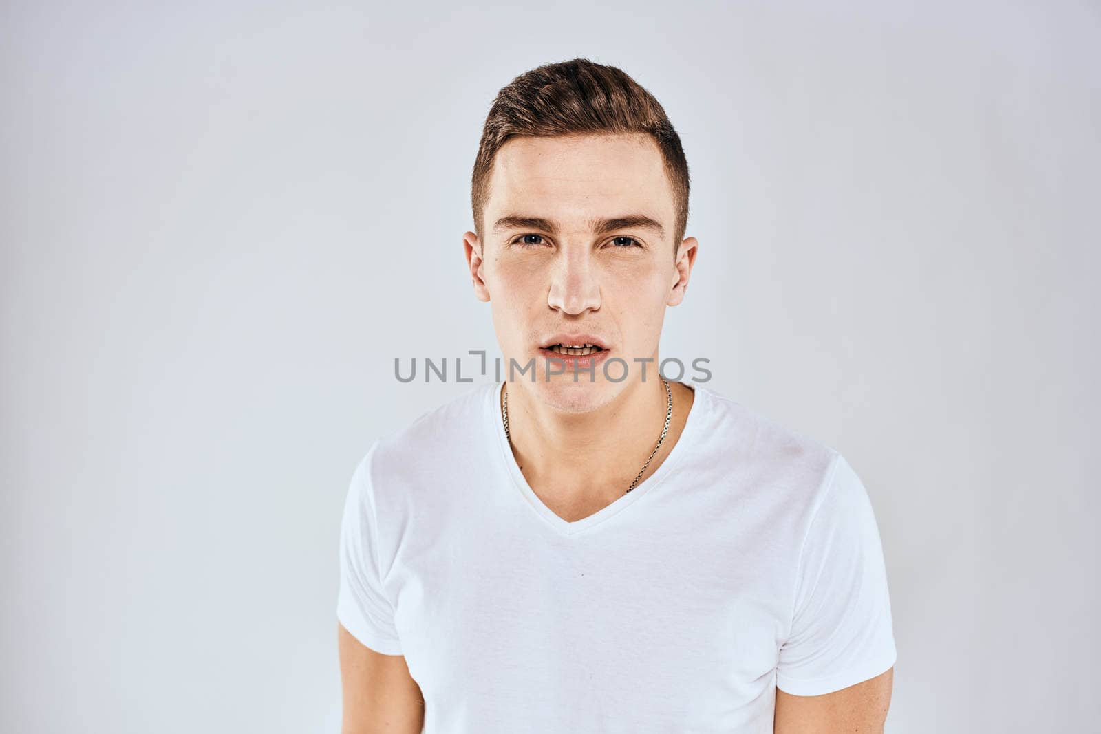 Nice man in a white t-shirt gestures with his hands emotions surprise studio. High quality photo