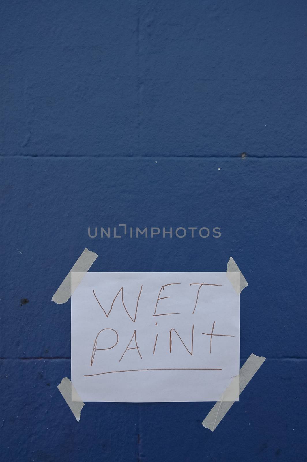 Wet Pain paper sign on blue wall